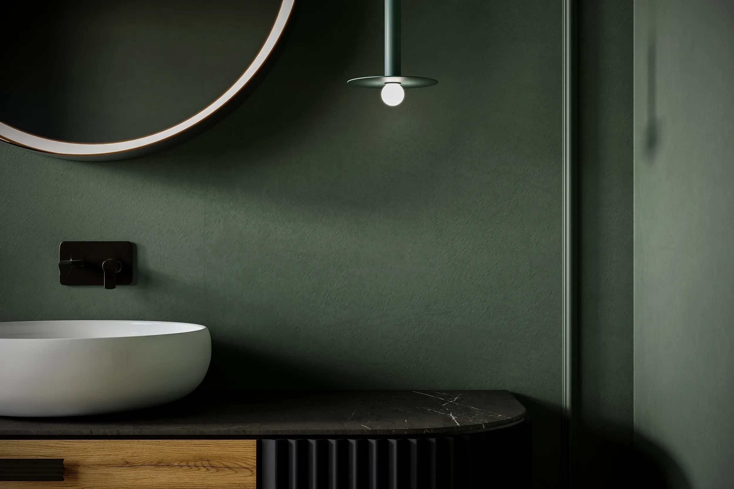 Close-up of modern bathroom with green textured wall, round mirror with LED lighting, black electric outlet, white porcelain vessel sink, and glass shower wall with chrome fixtures.