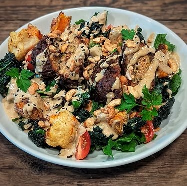 Salad with cherry tomatoes, walnuts, blackberries, and greens on a white plate.