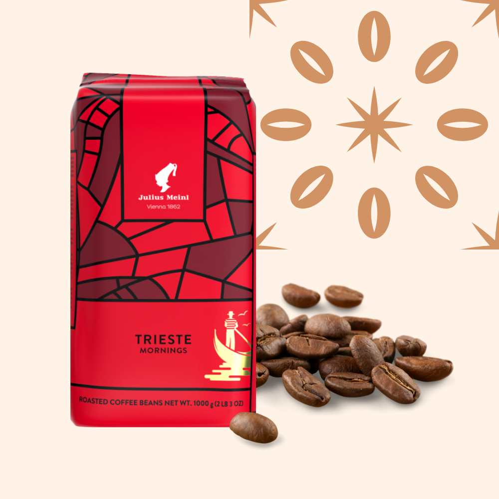 A red package of Julius Meinl Trieste Mornings roasted coffee beans with scattered coffee beans and a decorative pattern in brown in the background.