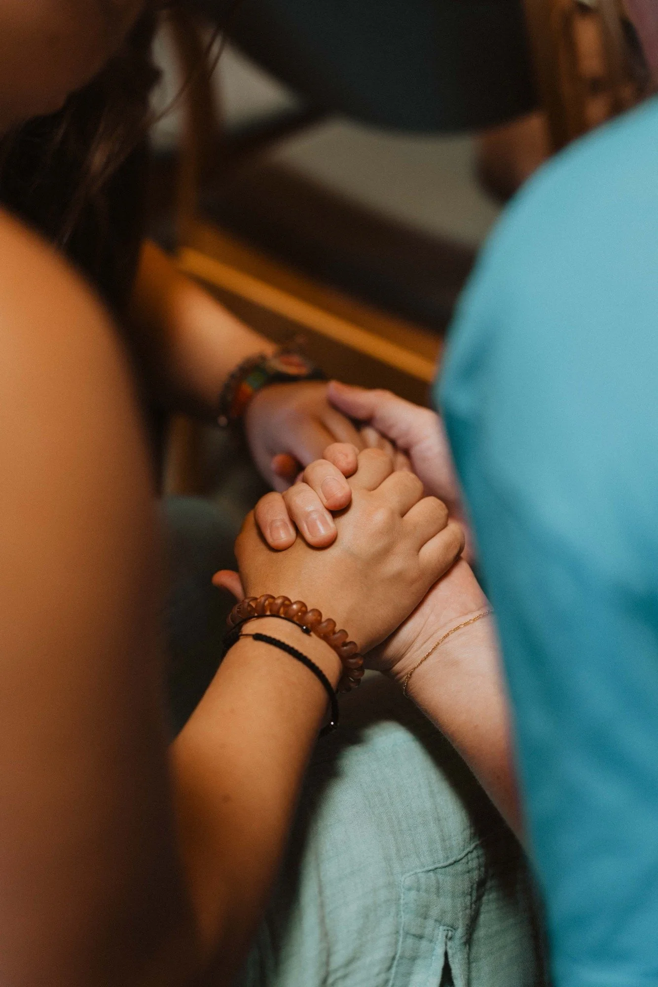 Two people holding hands in a close embrace, with one person's hand gently grasping the other's in a supportive manner.