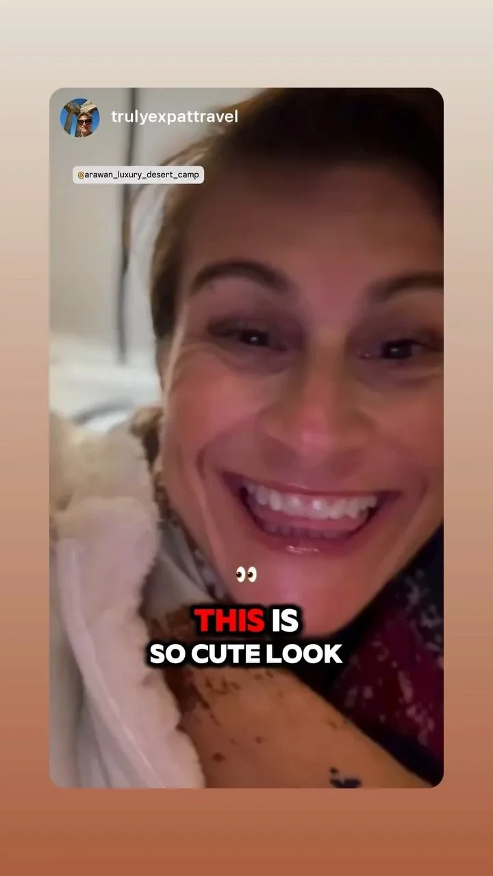 Close-up of a smiling woman with light brown hair, visible freckles, and a tattoo on her arm, with text overlay that says 'THIS IS SO CUTE LOOK' in bold red and white letters.