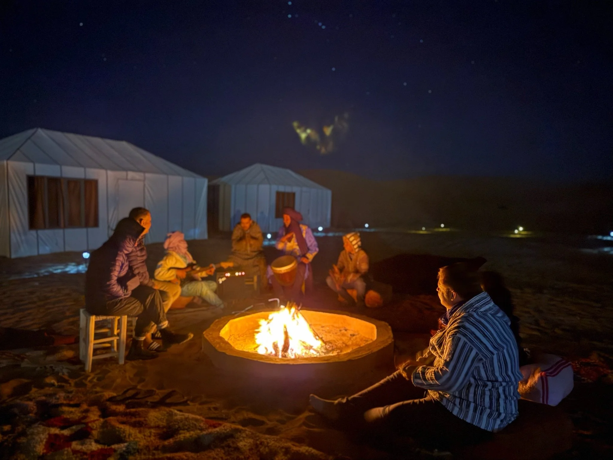 At  night music and storytelling happen under the stars as people sit and enjoy a bonfire and dancing.