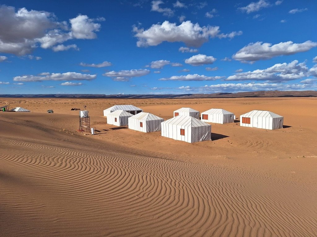 Arawan Luxury Desert Camp from above in the dunes that  have had lines carved into the sand from the wind. Arawan sits peacefully below.