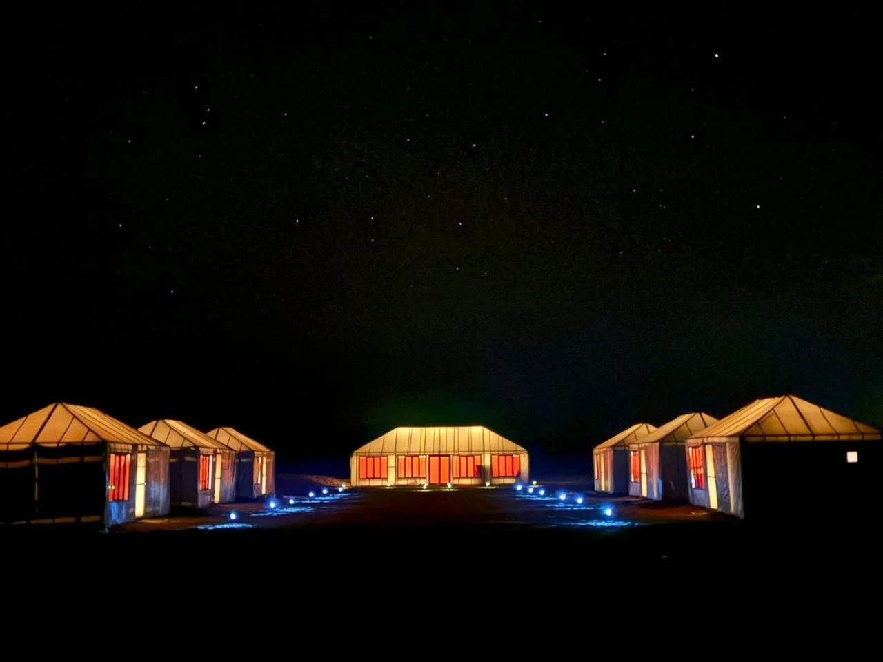 A series of illuminated tents set against a starry night sky.