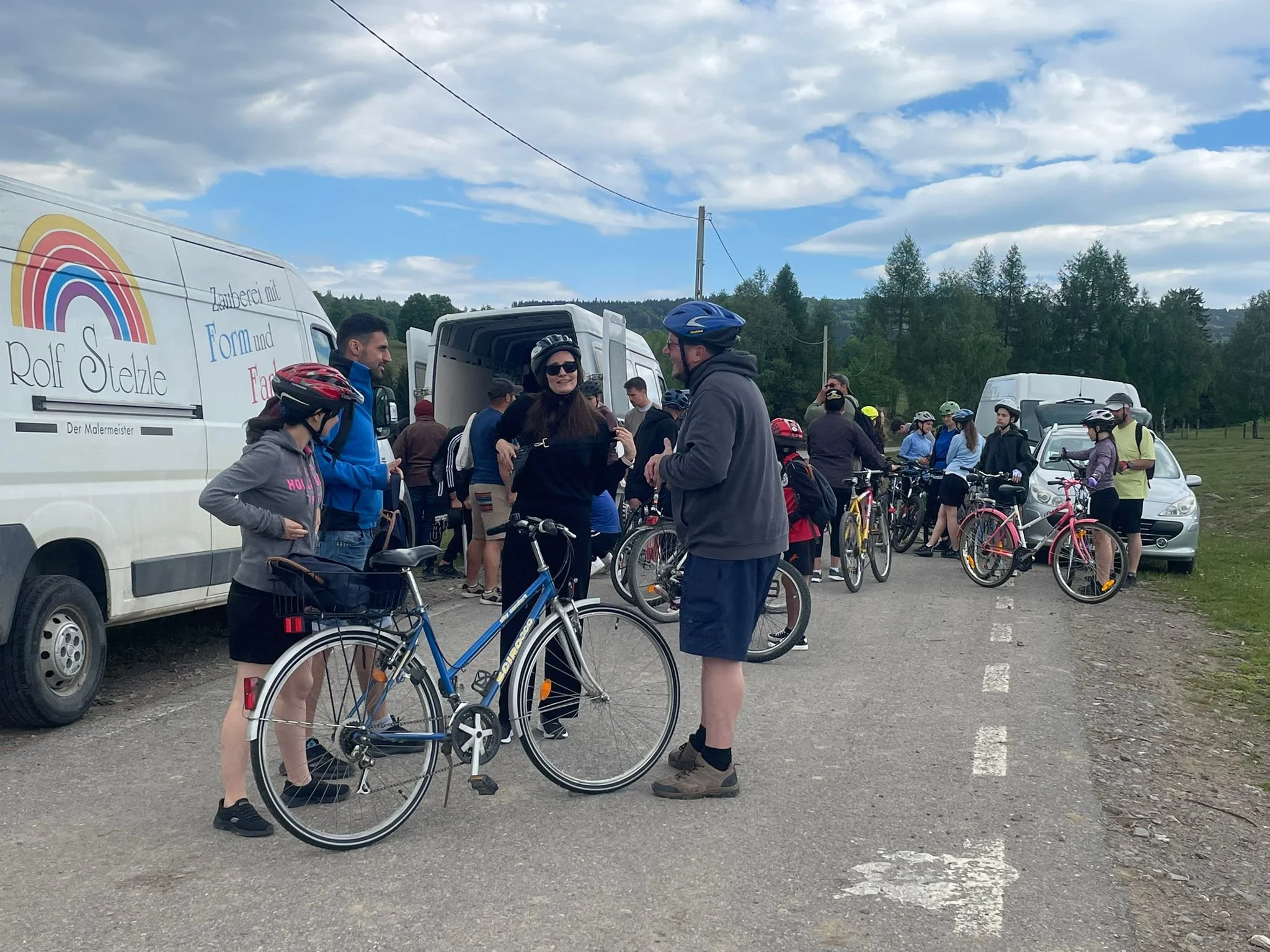 4 Menschen stehen um ein Fahrrad, dahinter steht ein Transporter mit einer offenen Hecktür