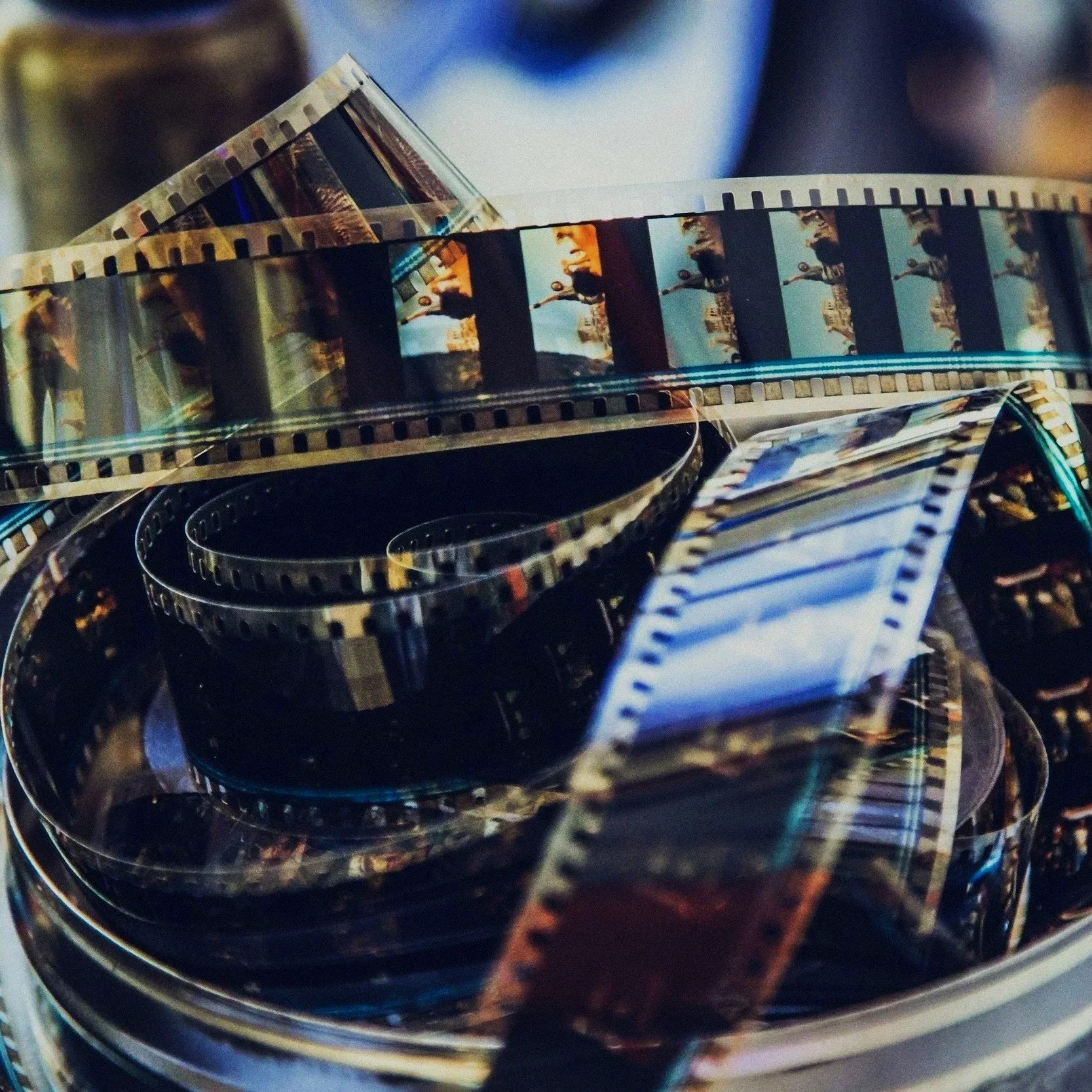 A pile of movie film reels with film strips unwinding from the reels.