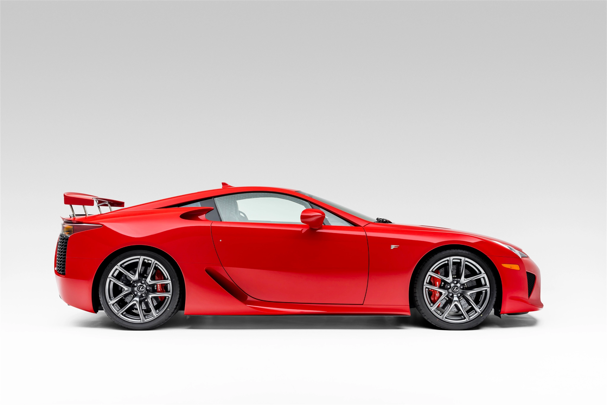 A red Lexus LFA shot side-on in a photo studio.
