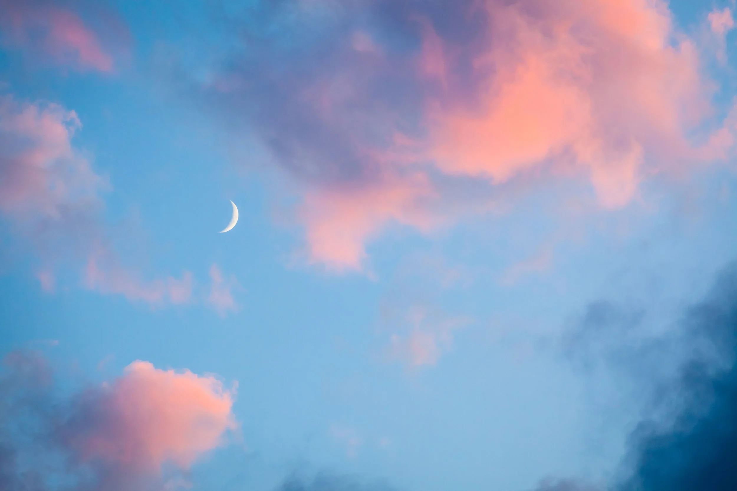 Sky with pink clouds and a crescent moon.