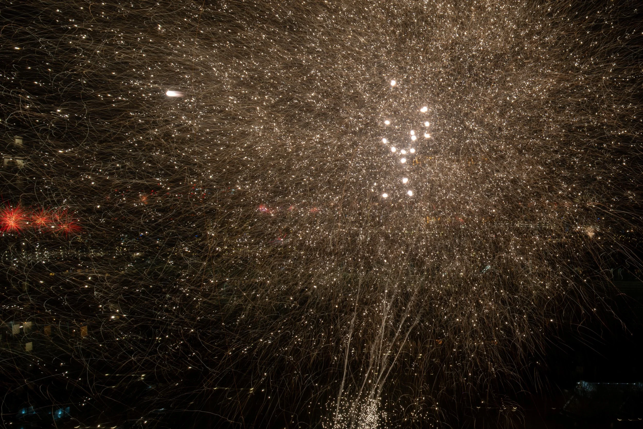 Fireworks exploding in the night sky with bright sparkles and streaks.