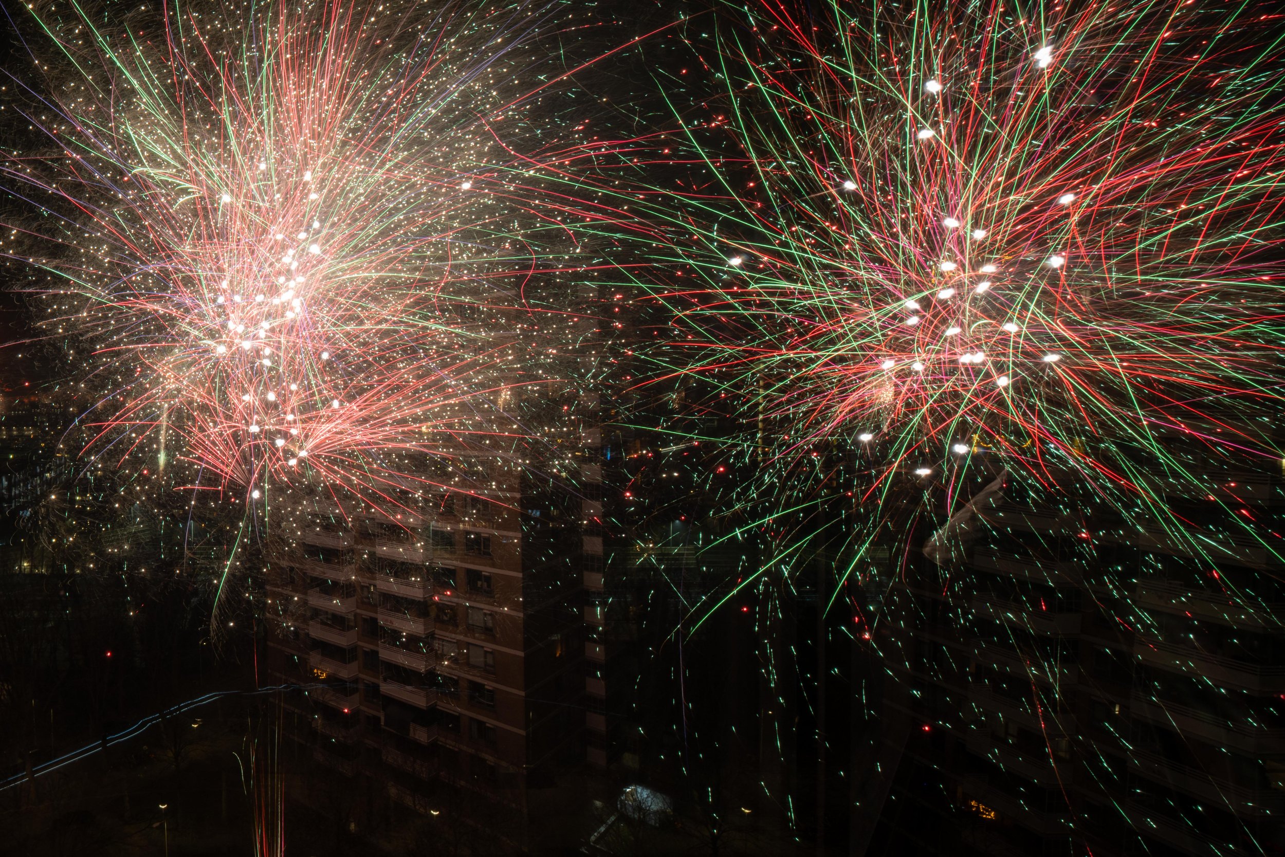 Colorful fireworks exploding in the night sky over a cityscape.