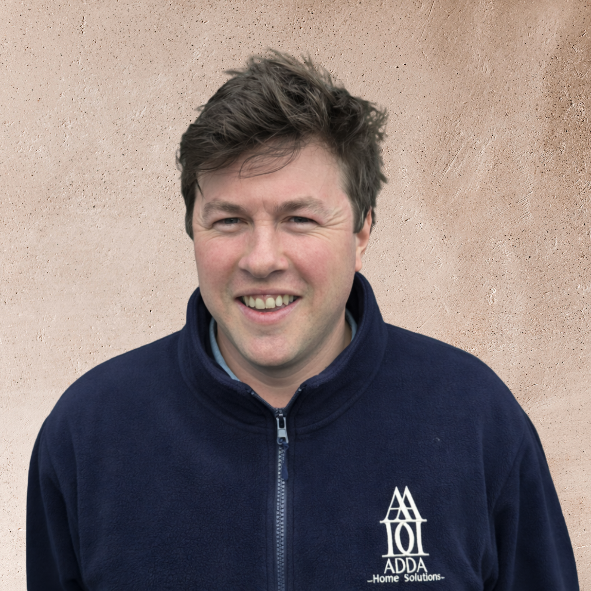 Young man with dark hair smiling and leaning against a tree in a park.