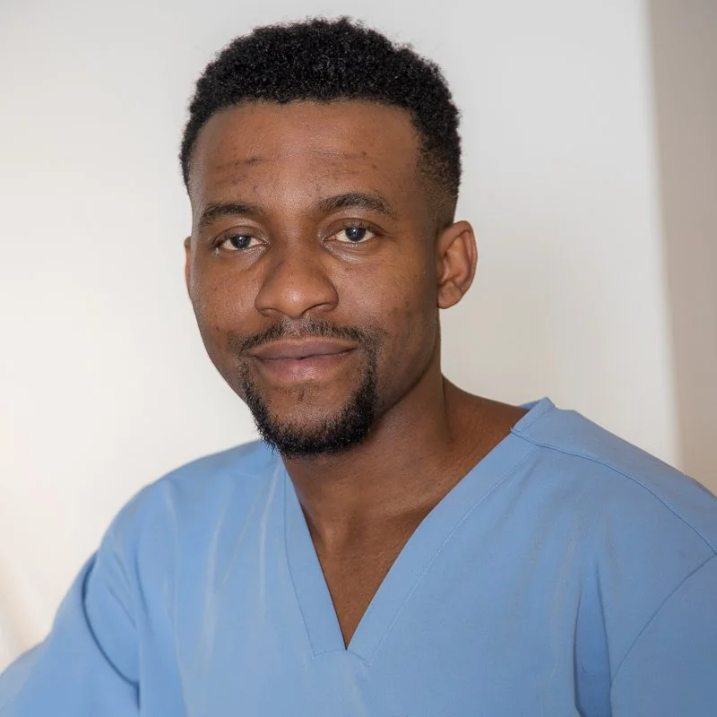 Mann in blauer medizinischer Kleidung vor hellem Hintergrund.