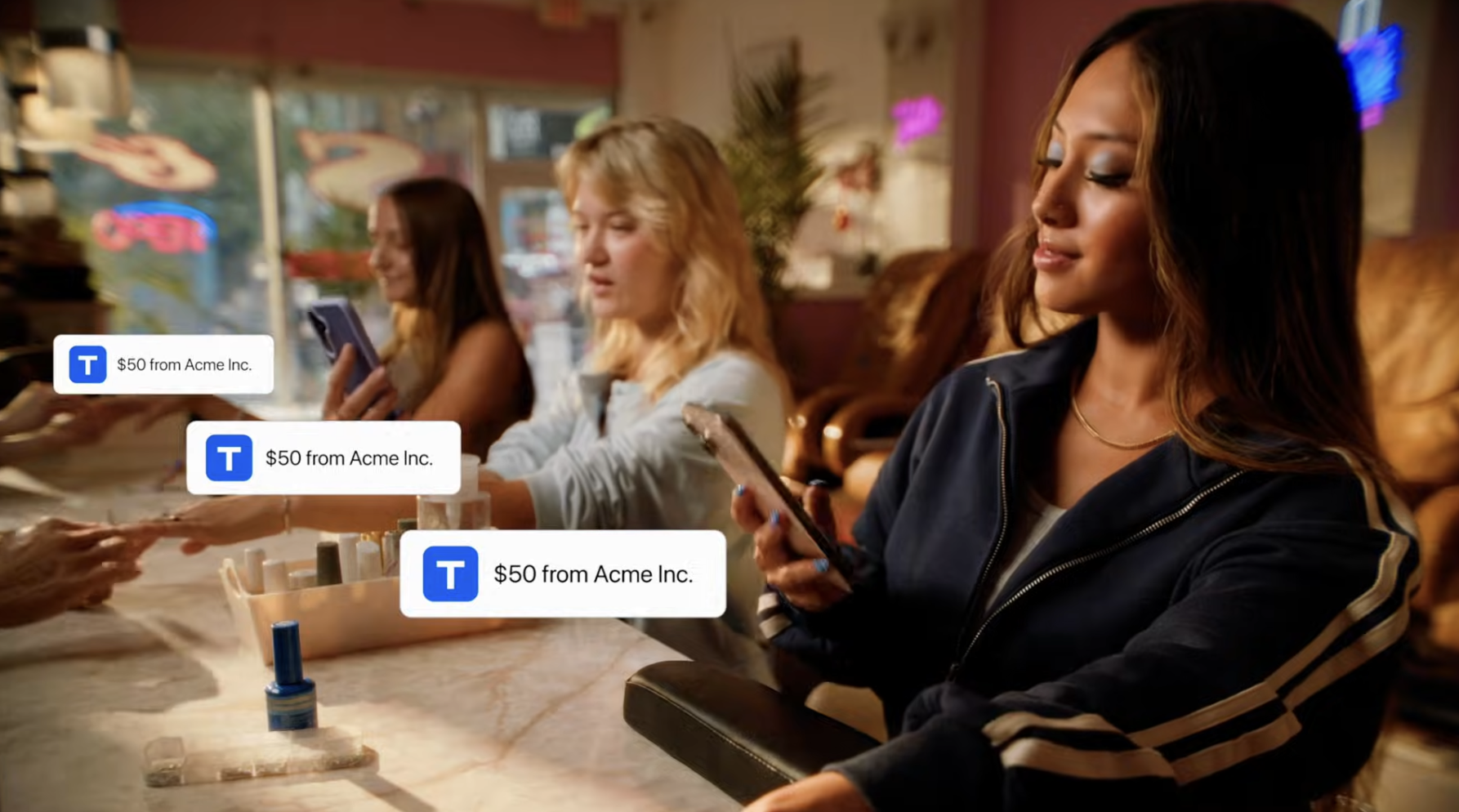 A group of women sitting at a table in a cafe, each looking at their smartphones, as seen in a commercial styled by Lindsay Foret, creatively invigorating the look and feel of film and tv commercial production in the Greater Philadelphia market.