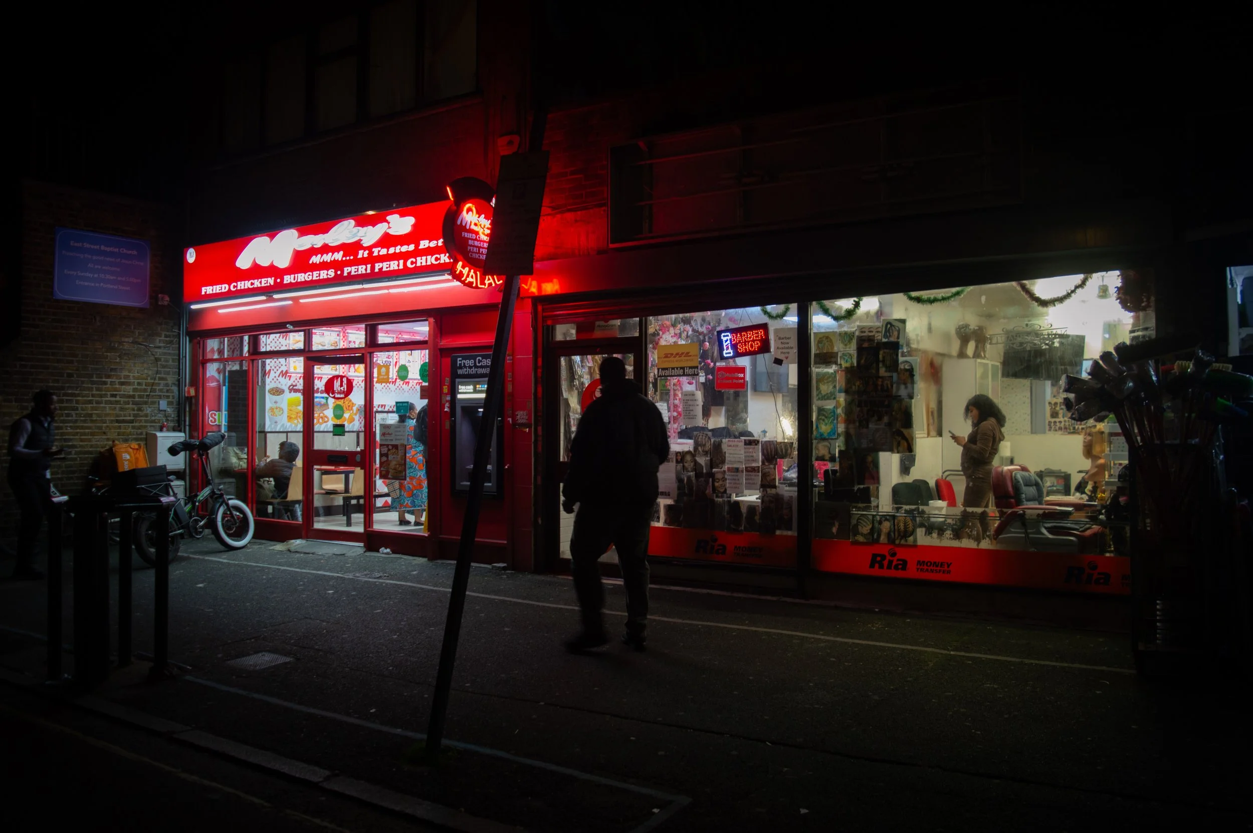 storefront landscape of the outside of morleys chicken shop and the black hair shop next to it at the end of East Street Market