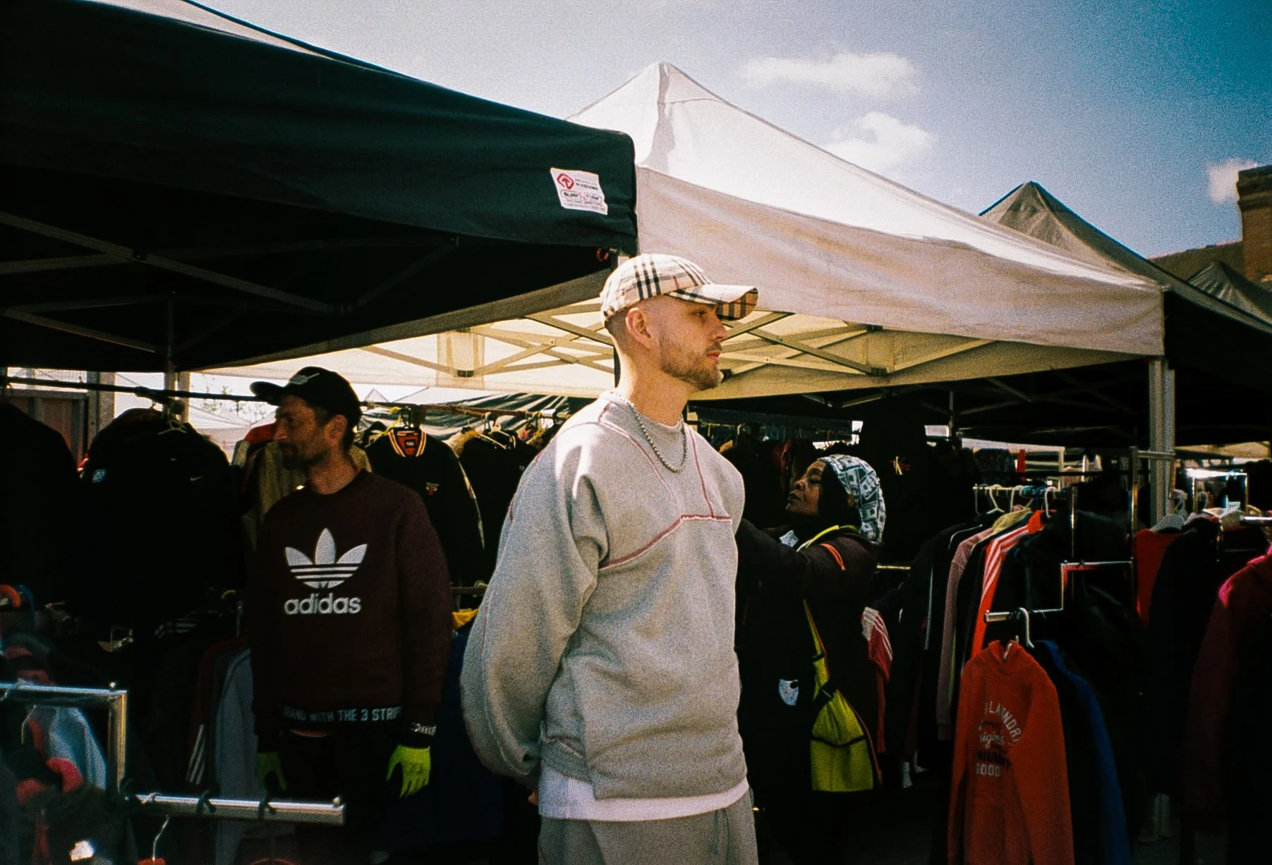 portrait of a young man facing away from the camera at a market in Dudley wearing aa tracksuit and Burberry baseball cap 