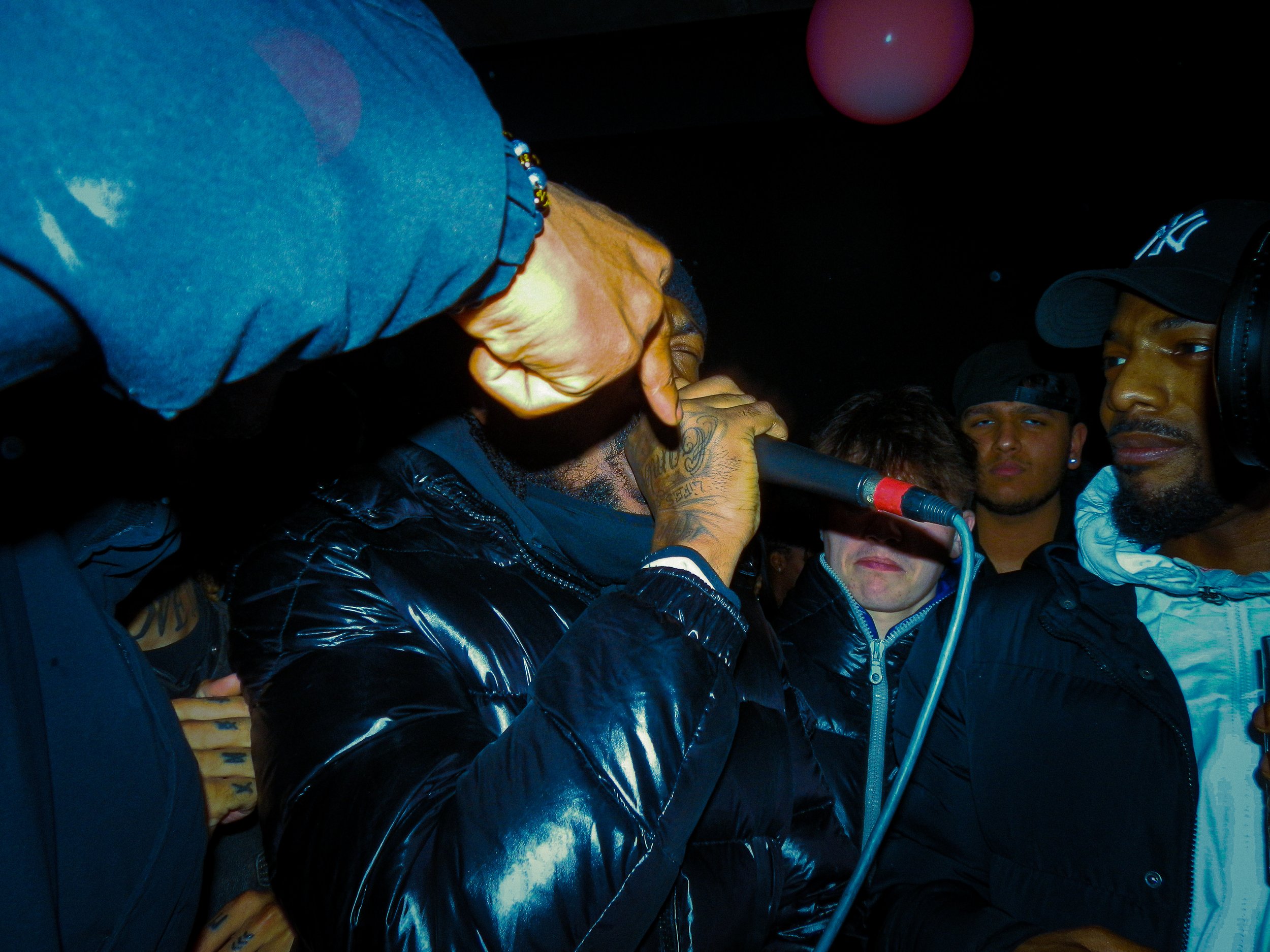 mc faultzy performing into a mic at travspresents rave in the middle of a crowd