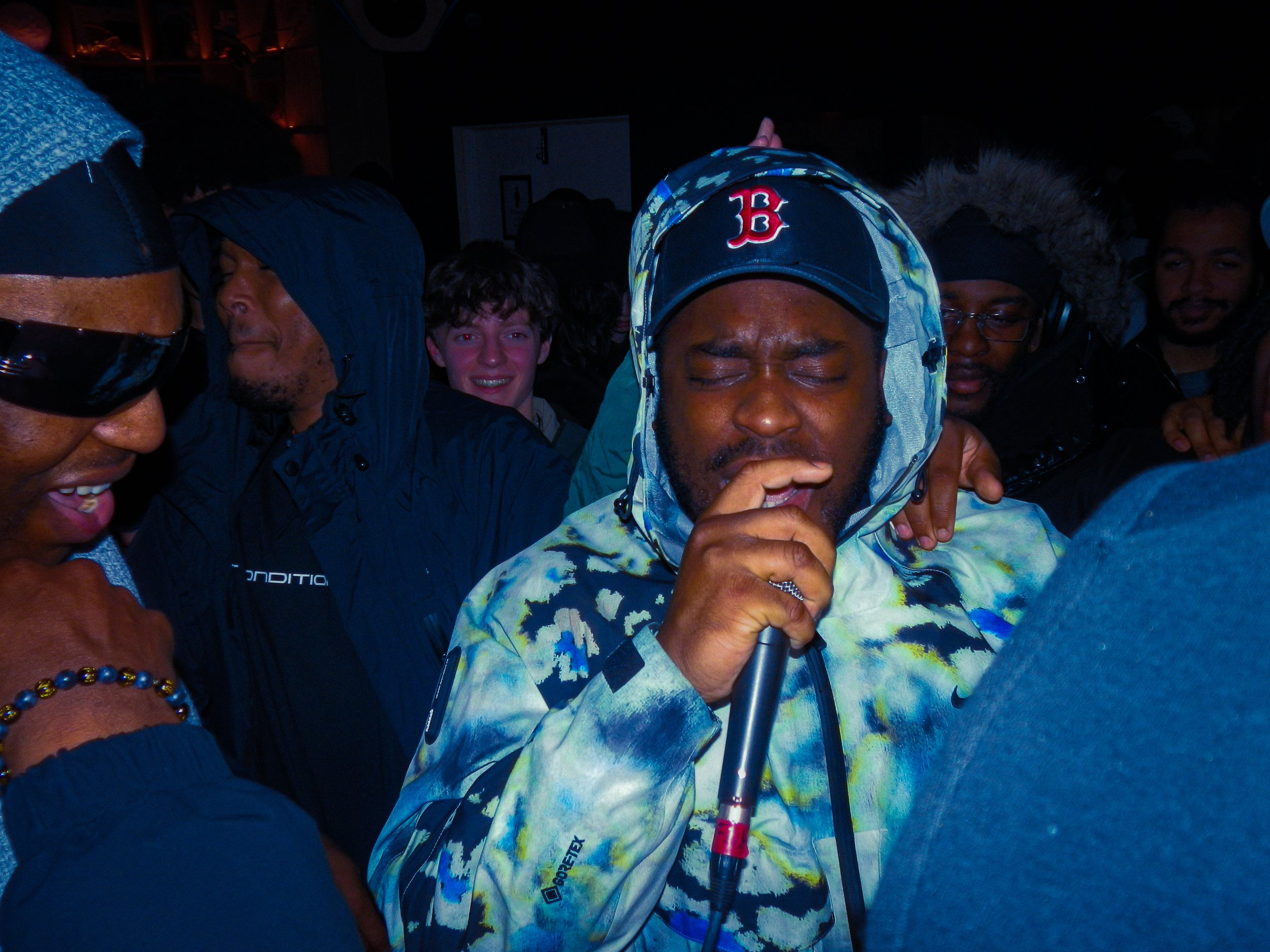 Mc Renz performing holding a microphone with a crowd surrounding him at a travs presents rave 