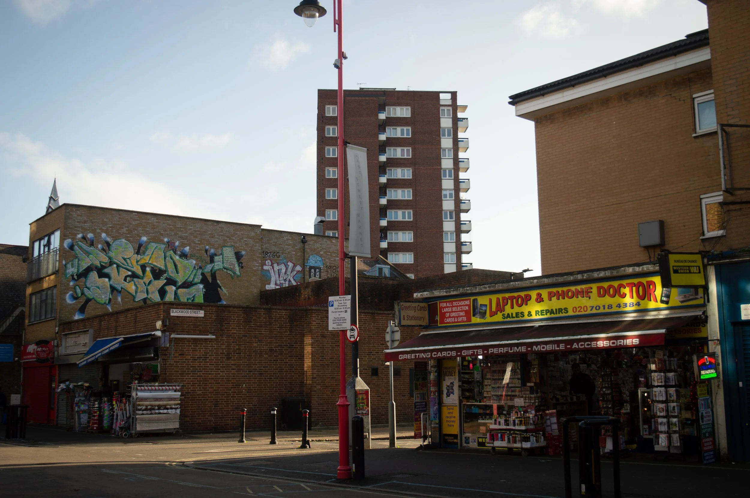 landscape of shops/street view at the end of East Street Market in Southwark with a tower block in the background