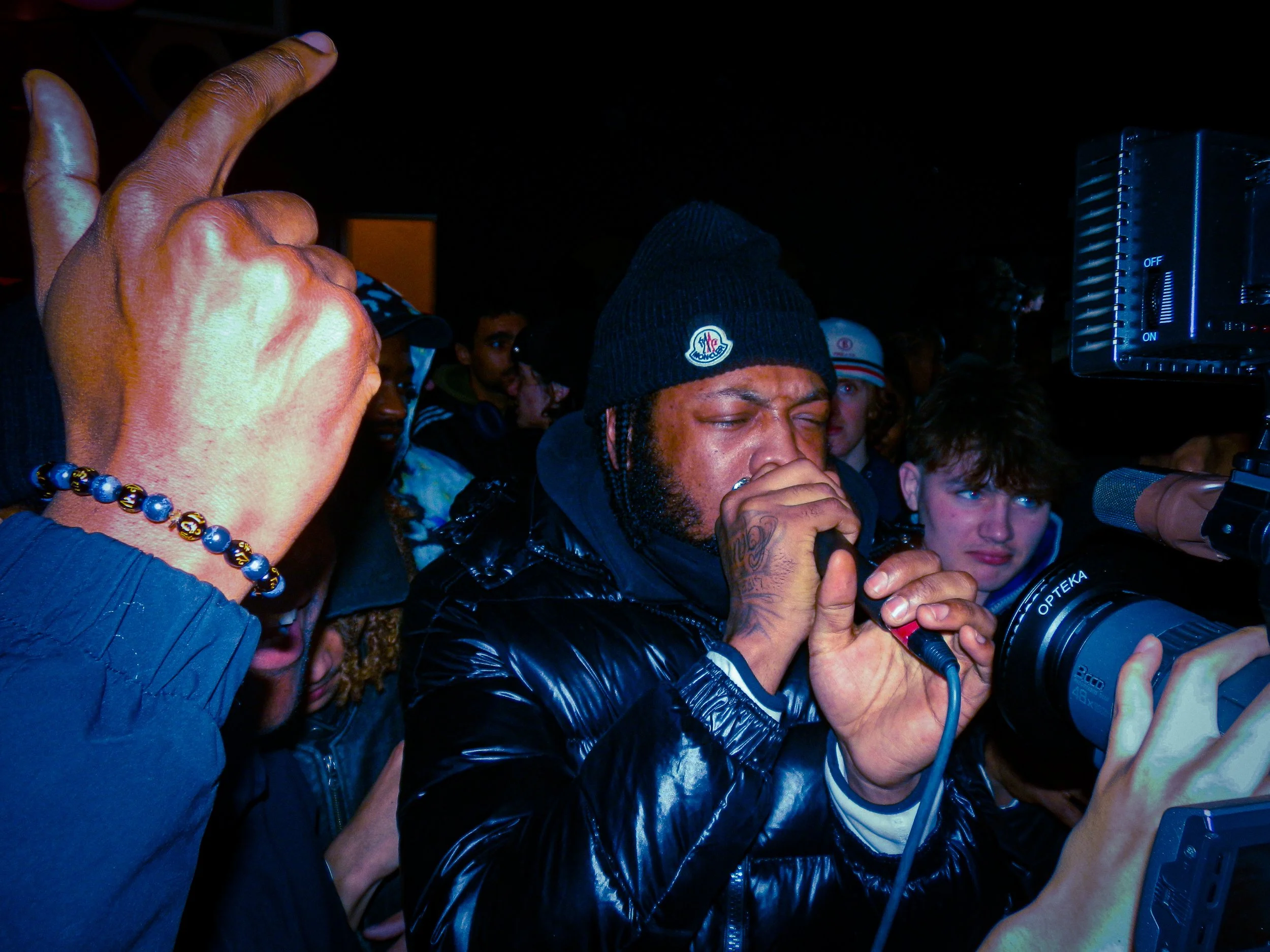 mc faultzy performing into a mic and camera at travspresents rave in the middle of a crowd