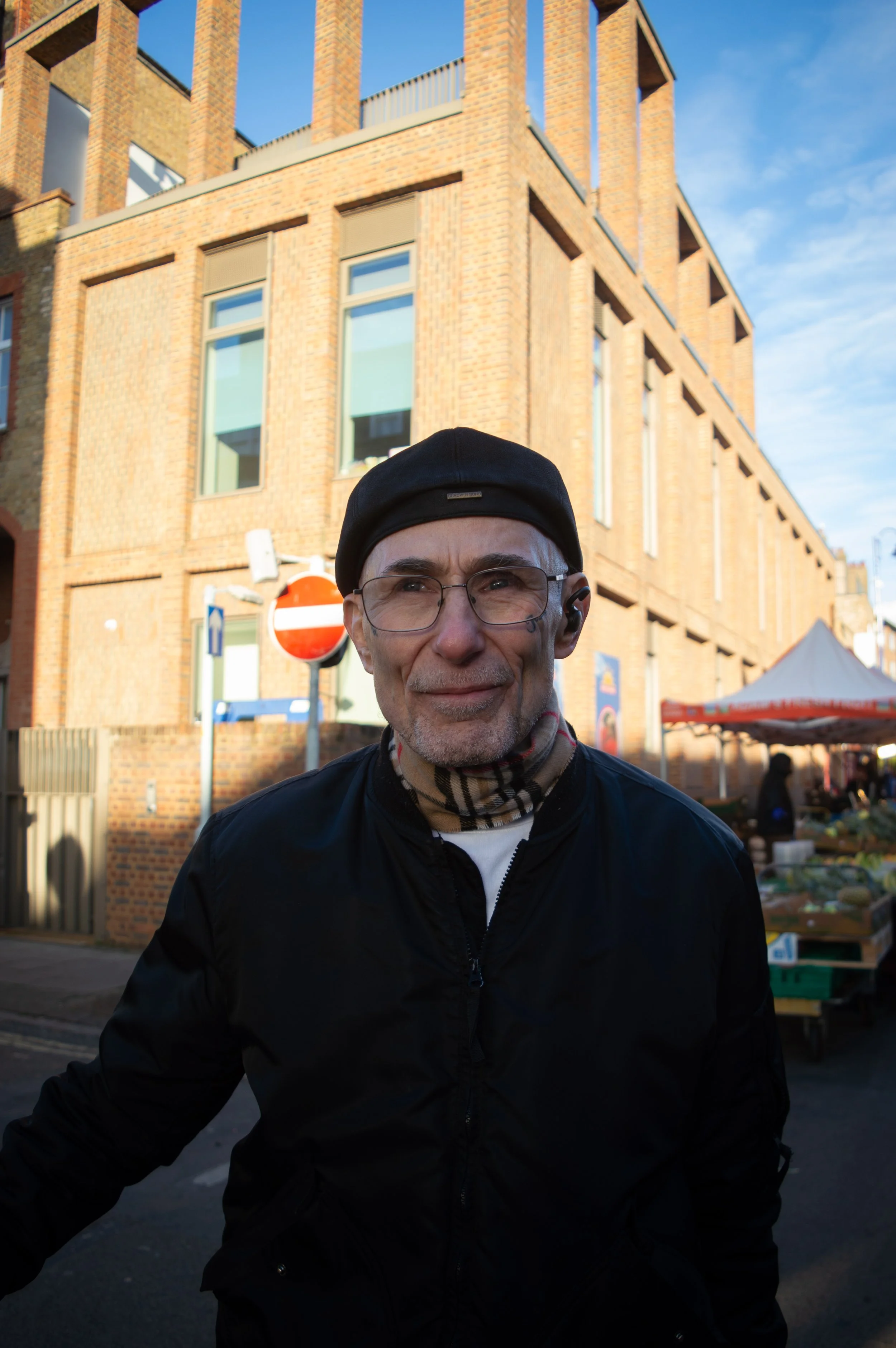 portrait of an elderly man with face tattoos with East Street Market in the background
