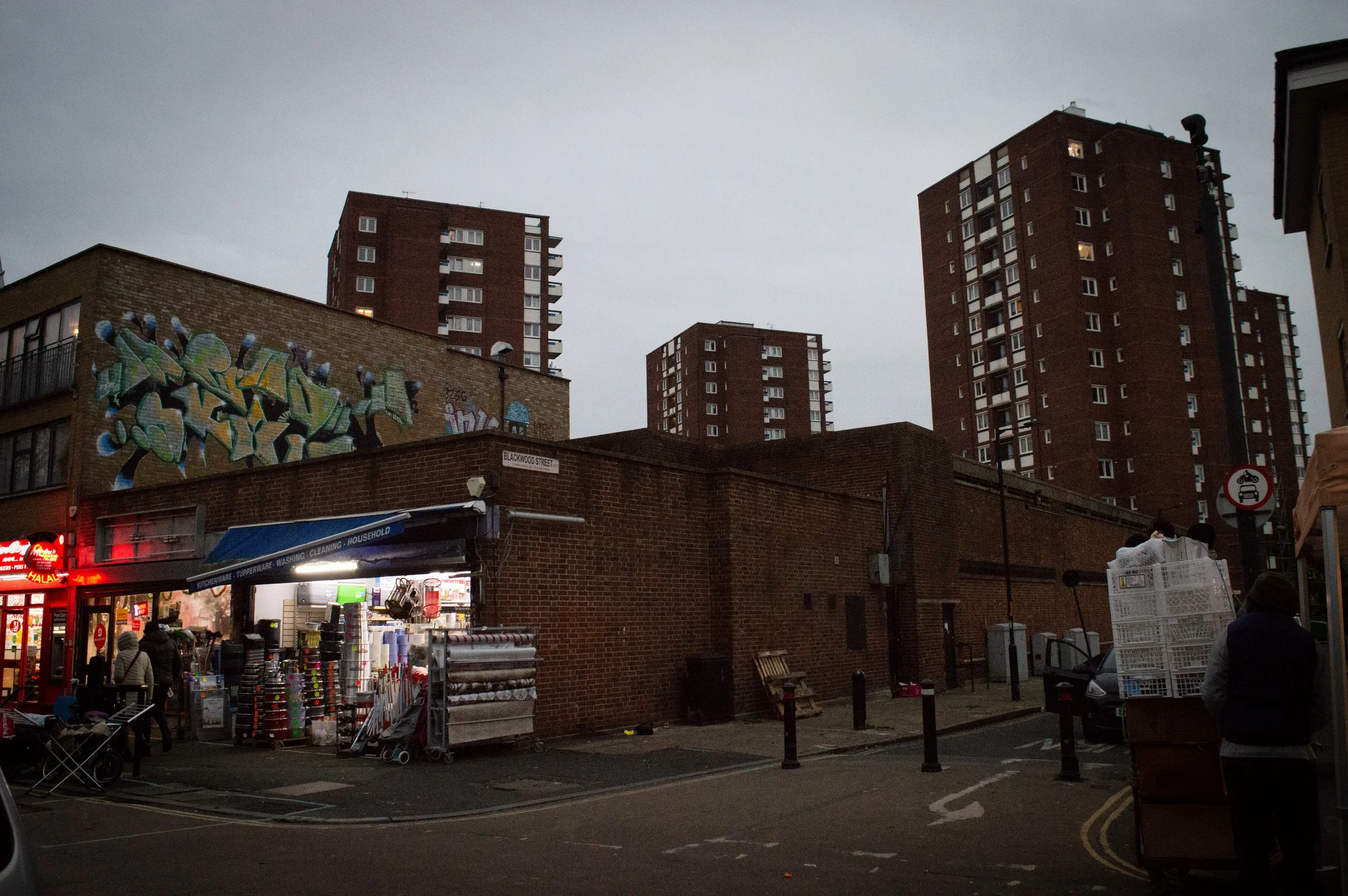 landscape of shops/street view at the end of East Street Market in Southwark with a tower block in the background