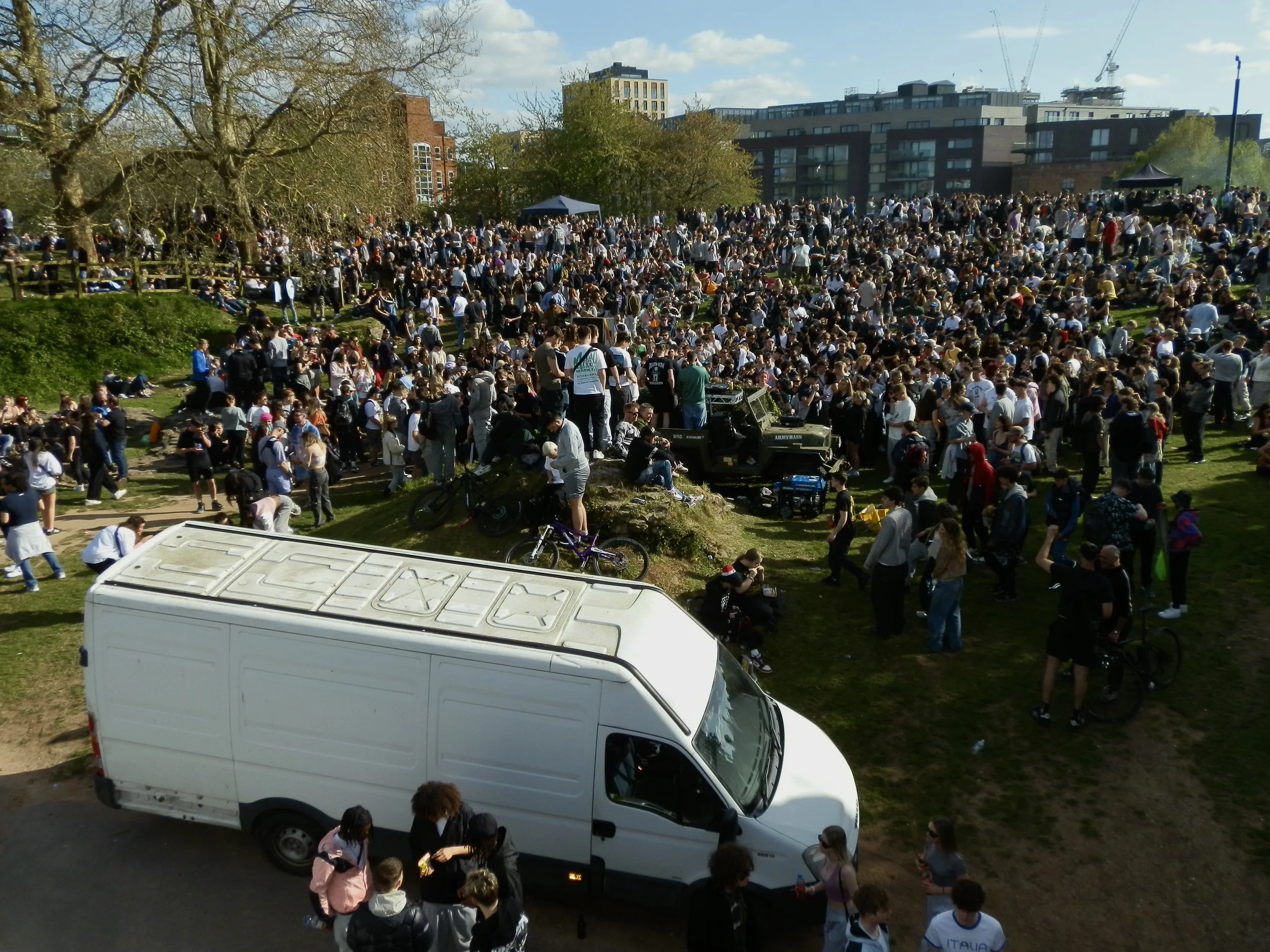 Street photography of a white large van in the bottom left of the image with a crowd filling the rest of the photo on a sunny day for 4/20 in castle park Bristol