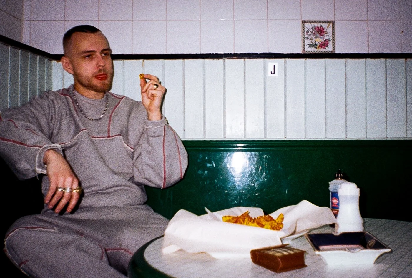 male model sitting at a table in greasy spoon cafe eating chipshop chips for Defenda menswear campaign
