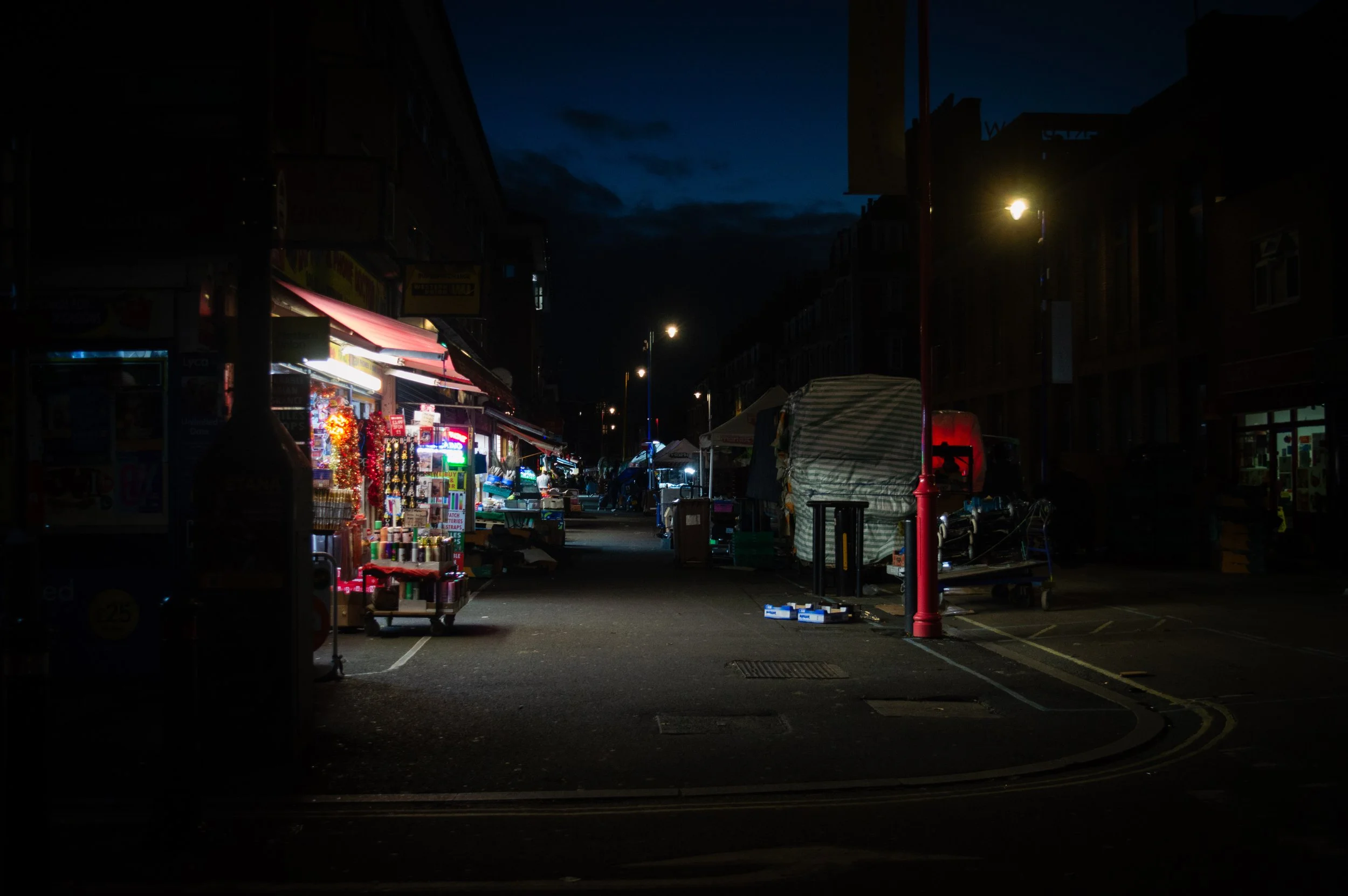 looking up the road of East Street Market in the evening with bright lights coming from shops