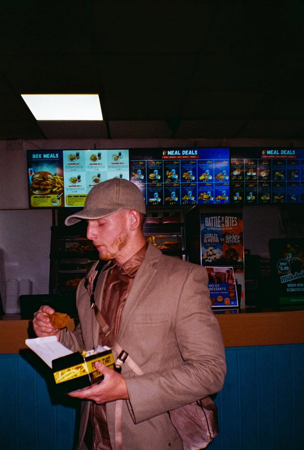 young man eating chicken and chips in chicken shop for Defends sportswear fashion campaign