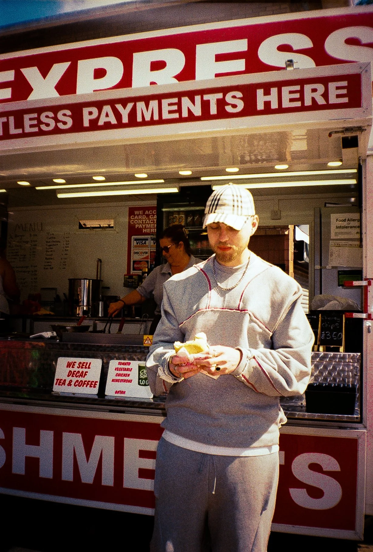 young man eating burger in front of a burger van for fashion campaign