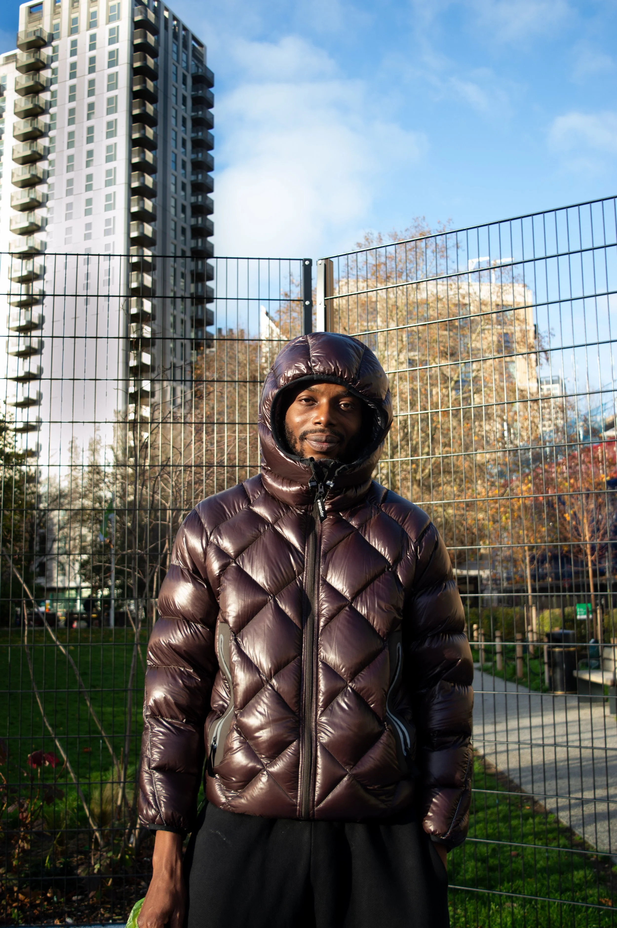 portrait of a young man named Fahad standing in a basketball court with a tower block in the background