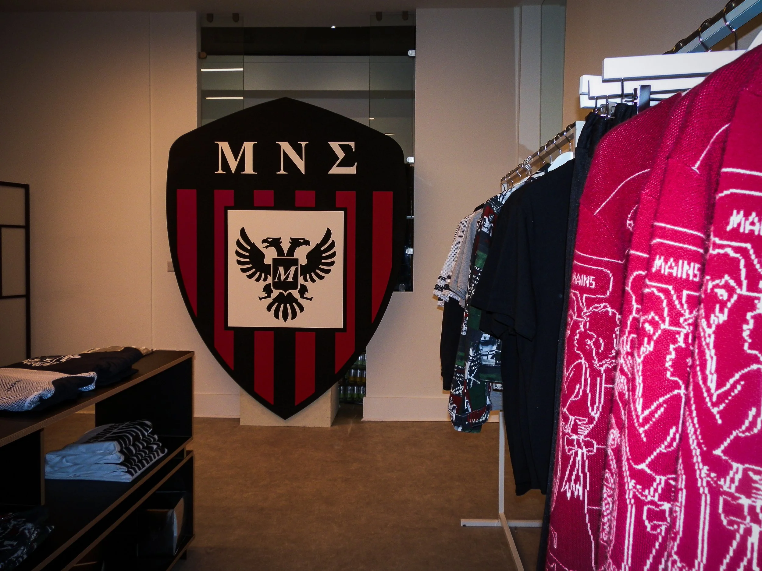 Mains pop up store, garments on clothing racks with the Mains logo sign in the background