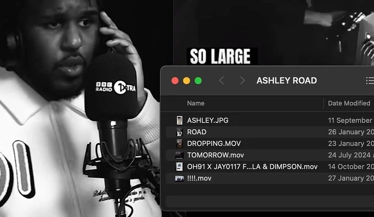 A person speaking into a microphone in a recording studio with a computer screen showing file names and a banner reading 'SO LARGE'.