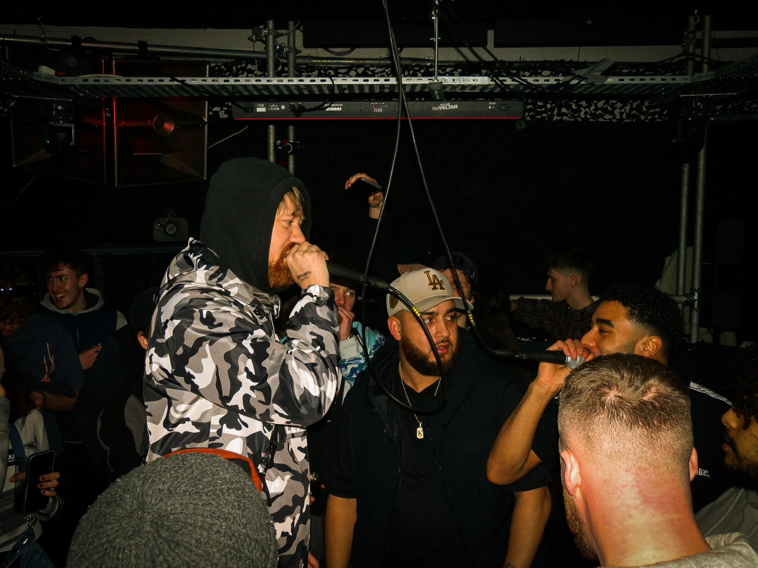 male mcs performing in the middle of a crowd at wheel up grime rave in norwich