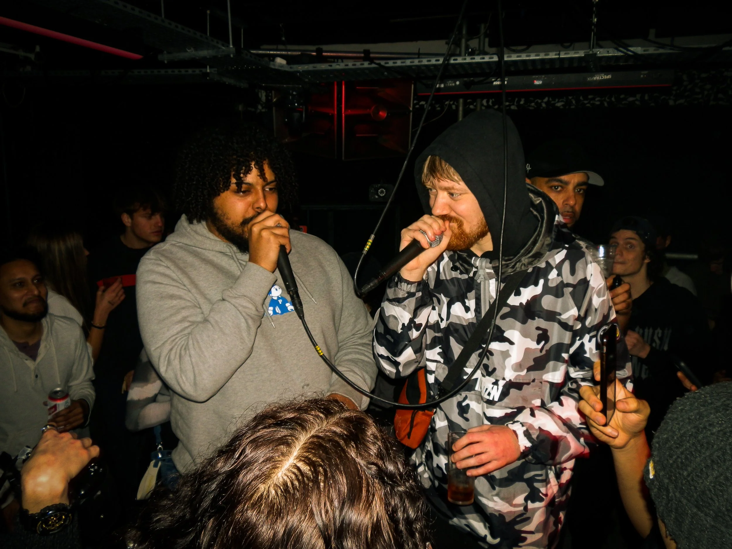 male mcs performing in the middle of a crowd at wheel up grime rave in norwich