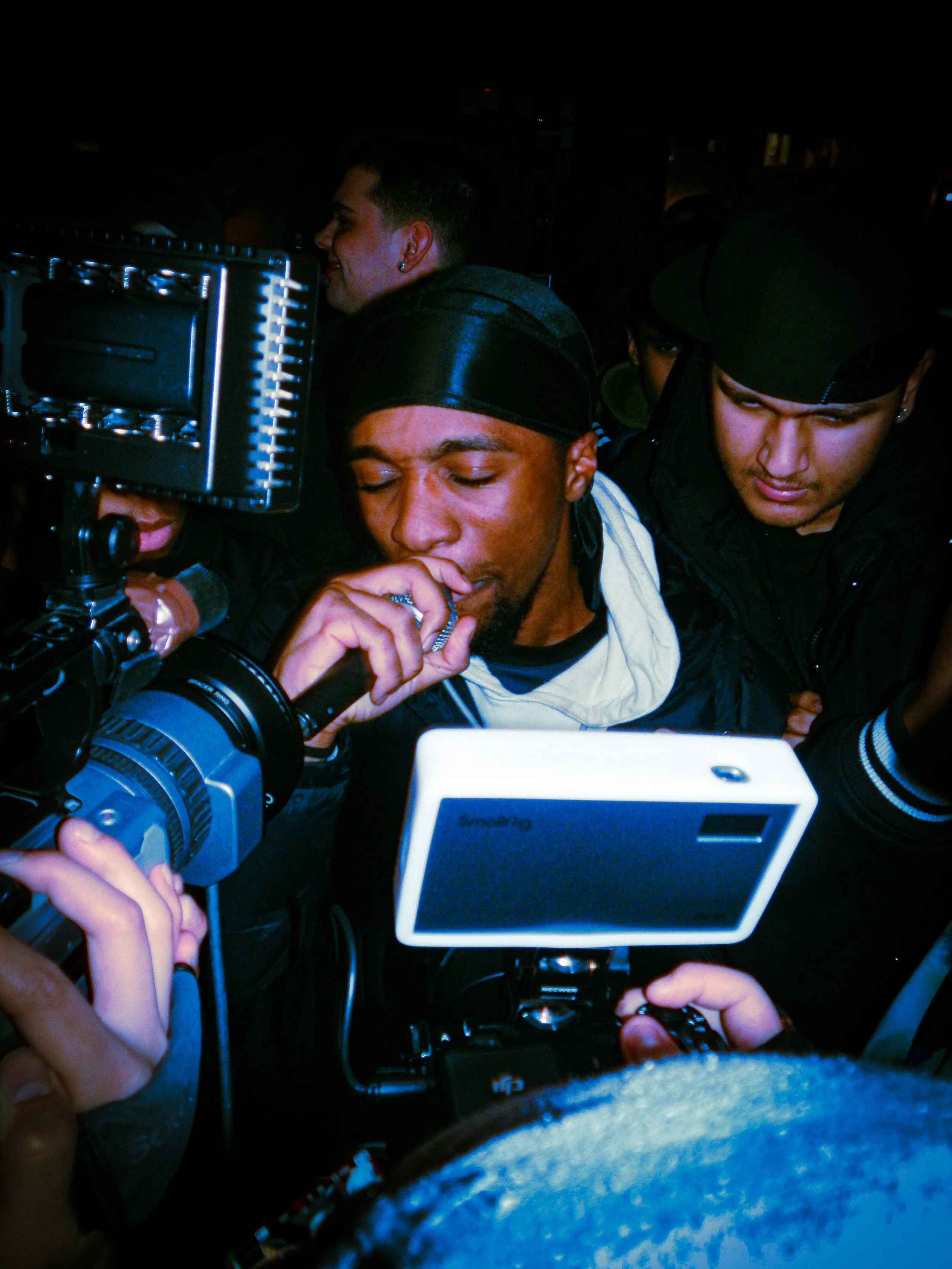 young mc performing at travspresents grime rave in the middle of a crowd with camcorders in his face