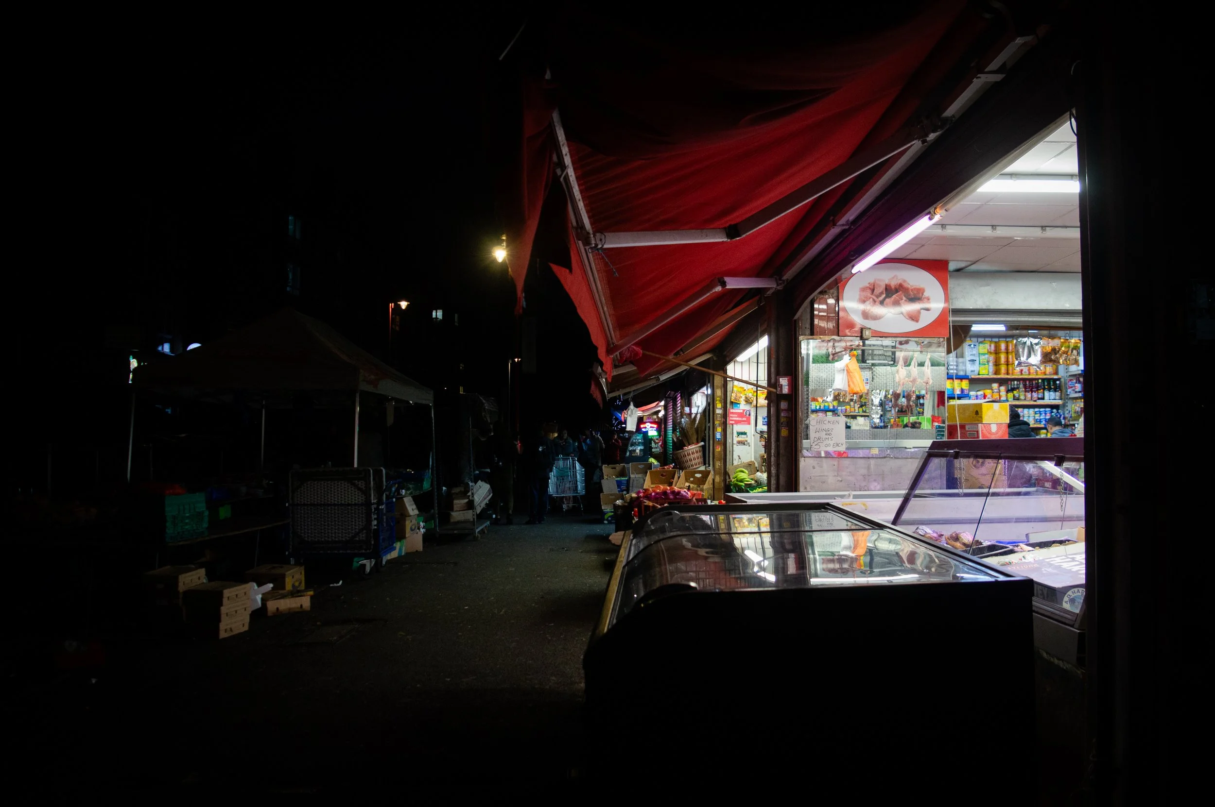 Street photography Landscape image of the side of a market style butchers with bright lighting 