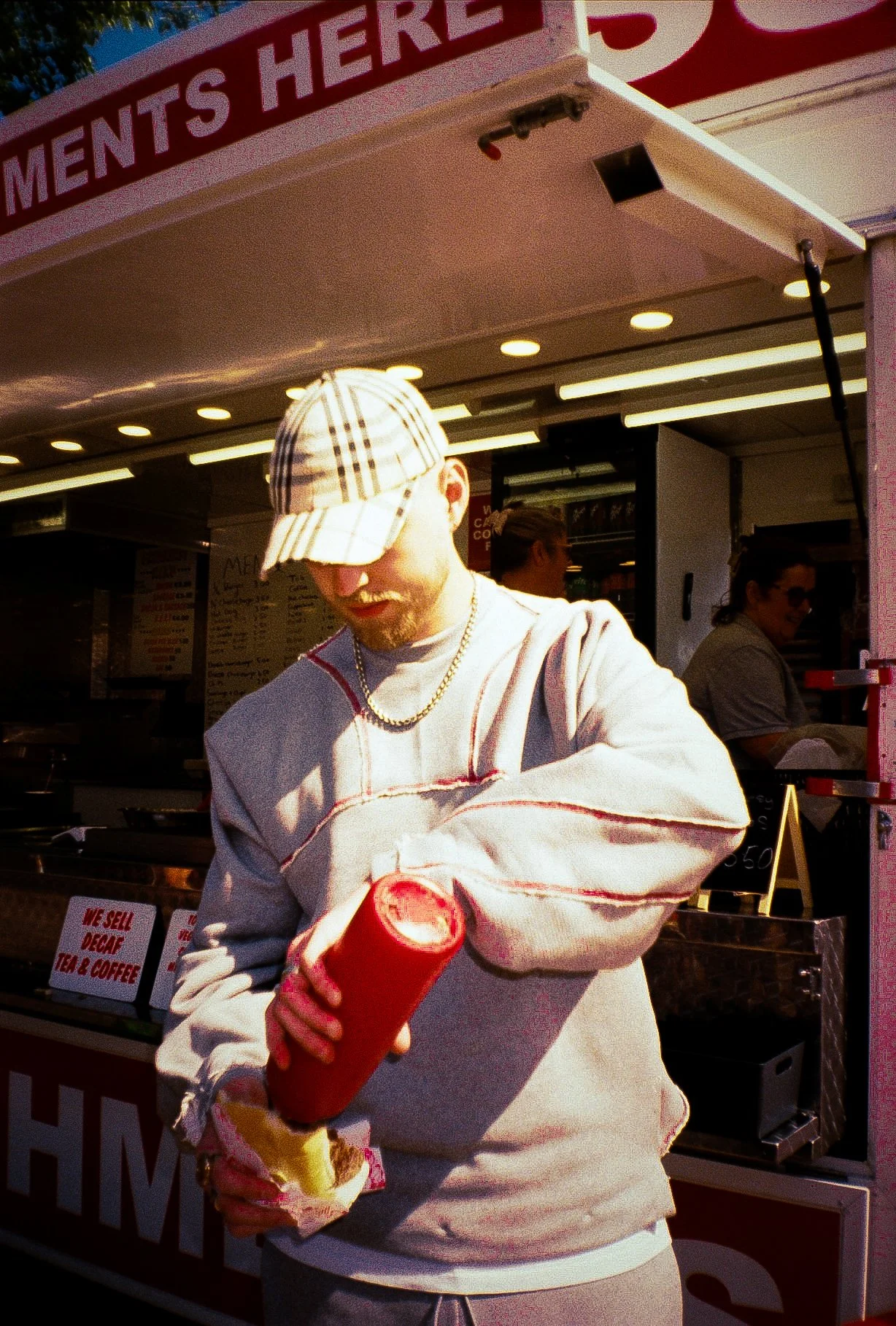 young man eating burger in front of a burger van