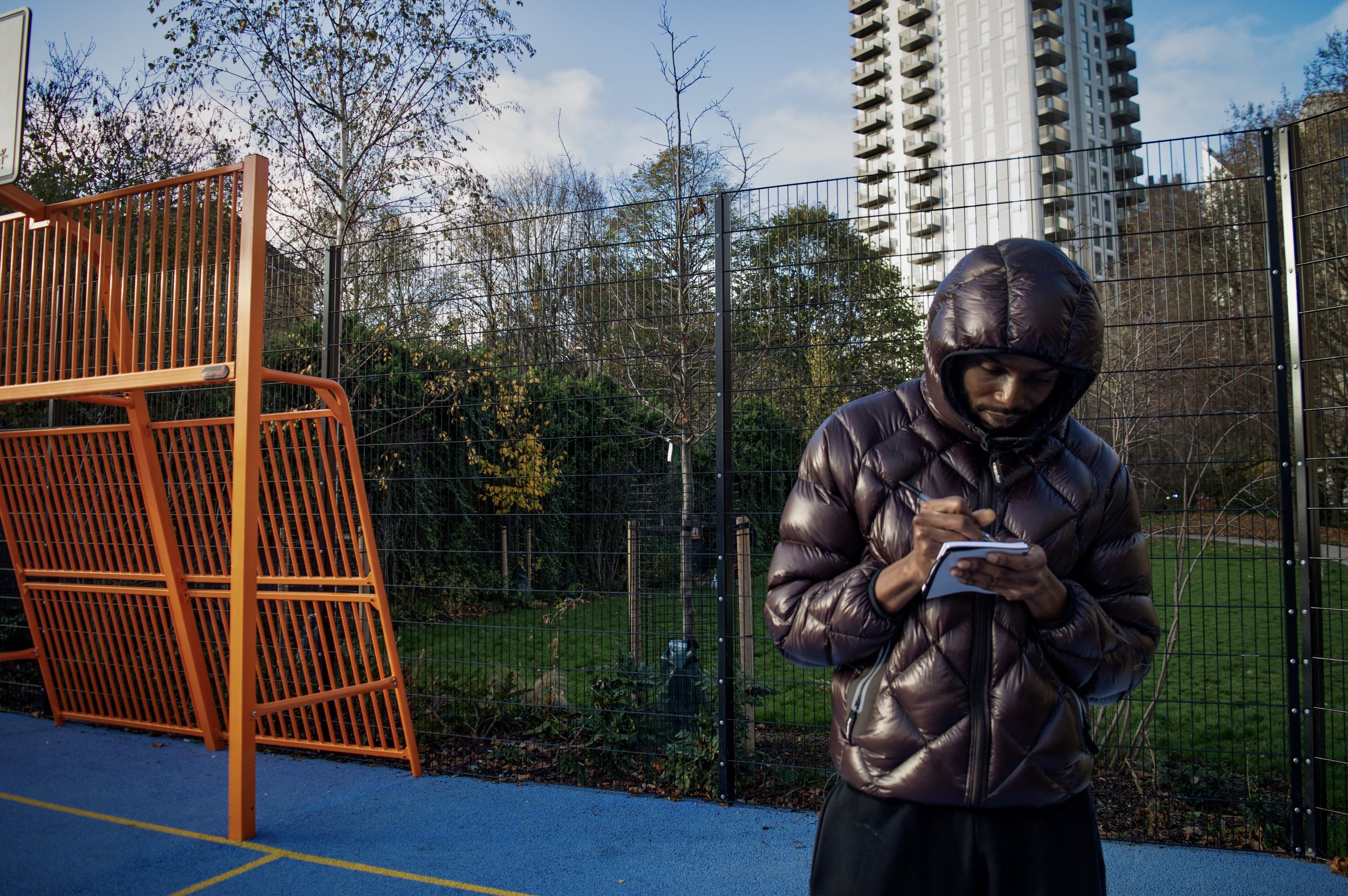 Portrait of Fahad who lives in Southwark writing down three words that come to mind when thinking about the area.