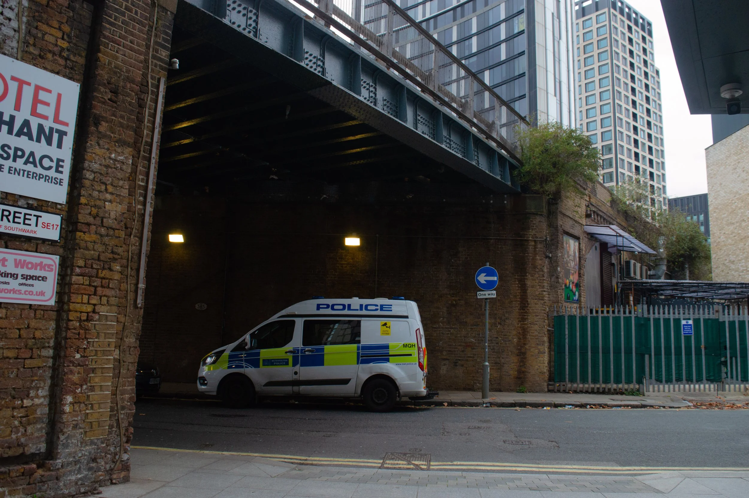 police van under a bridge with tall office buildings in the background in Southwark