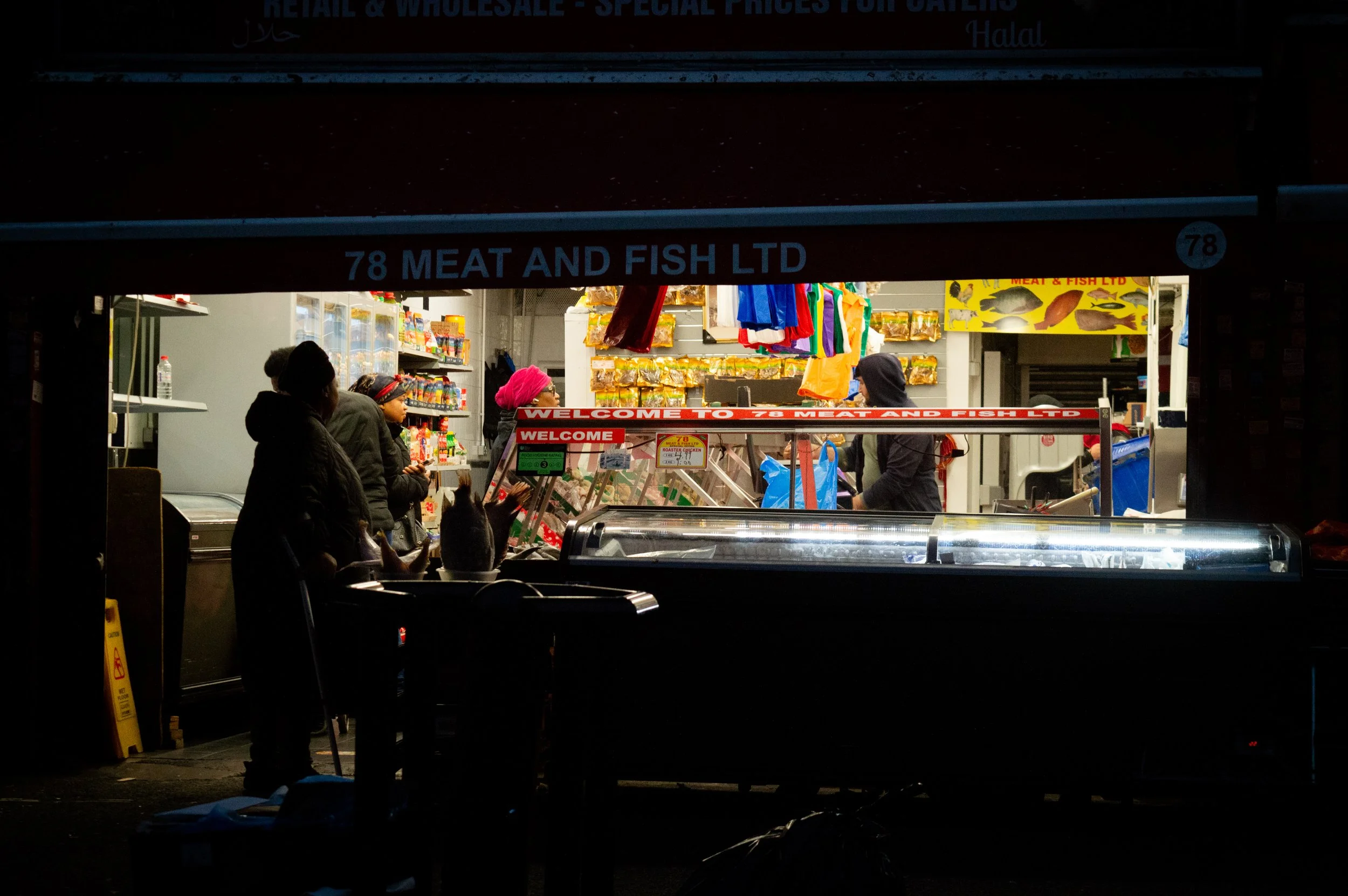 evening landscape of the outside of an indoor market style ethnic food shop with customers inside 