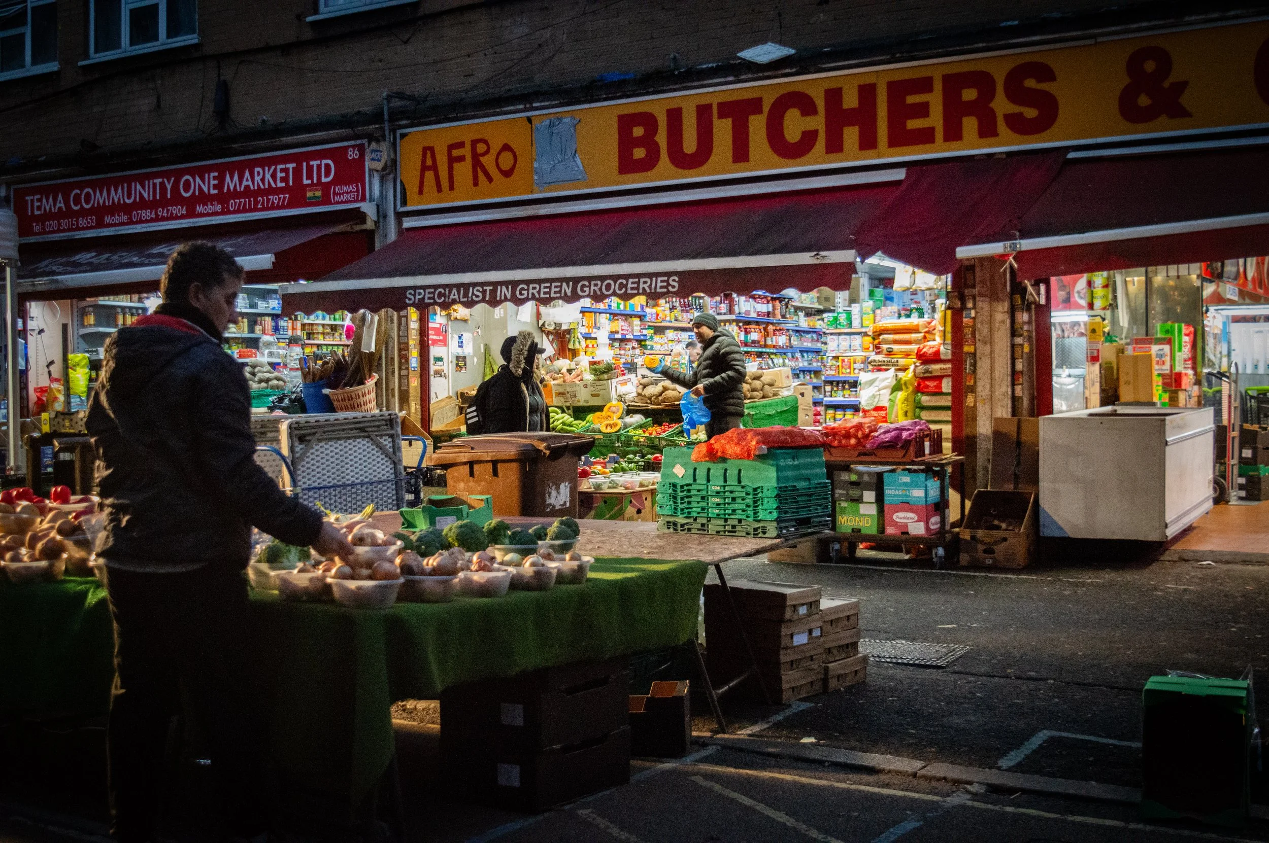 evening landscape of East Street Market with  an indoor market style ethnic food shop with customers inside in the background
