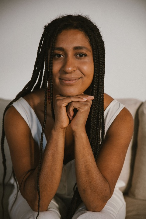Holiday Phillips with her family, sitting on a porch in front of a wooden door, smiling and laughing, with white and stone pillars on either side of the steps.