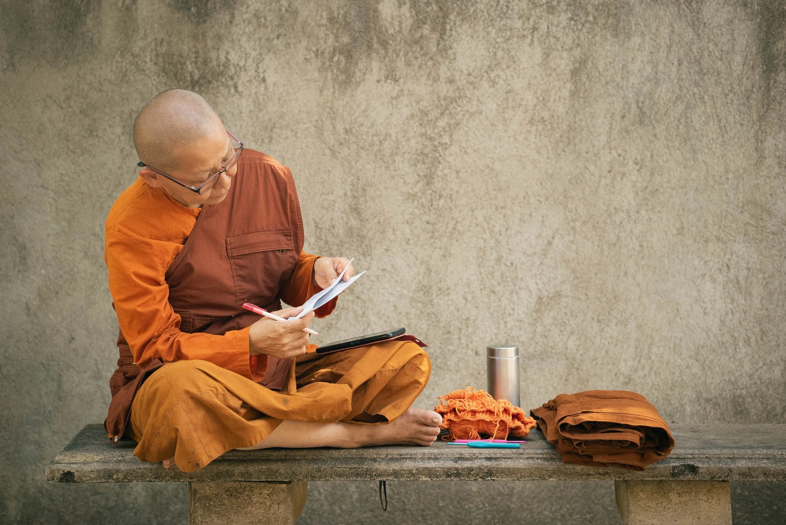 Bikkhuni Ayye Kamala is sitting on a bench and looking at Pali Chants to rehears for the Upasampada ceremony
