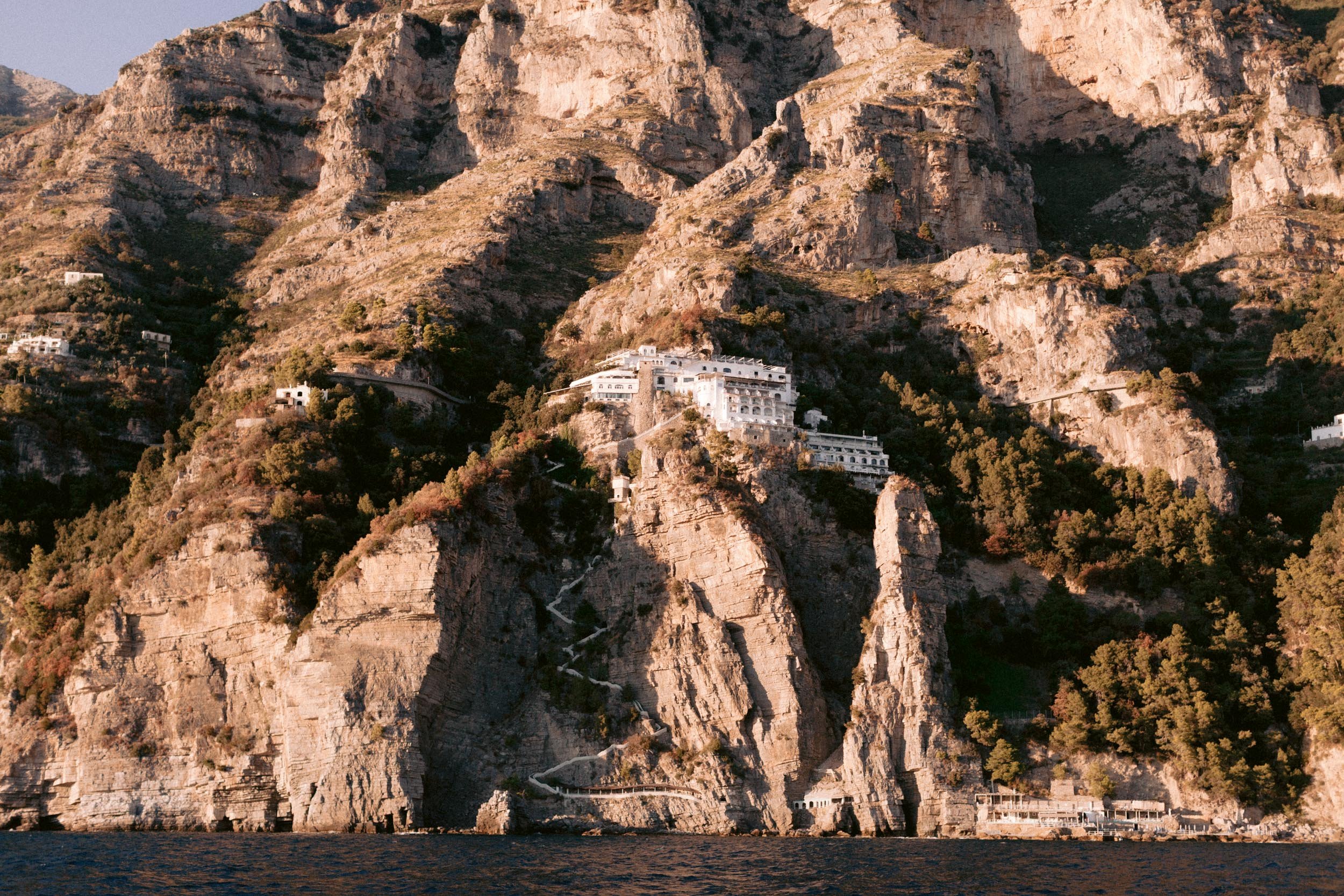 Cliffs along the water with white buildings built into the rocky hillside.