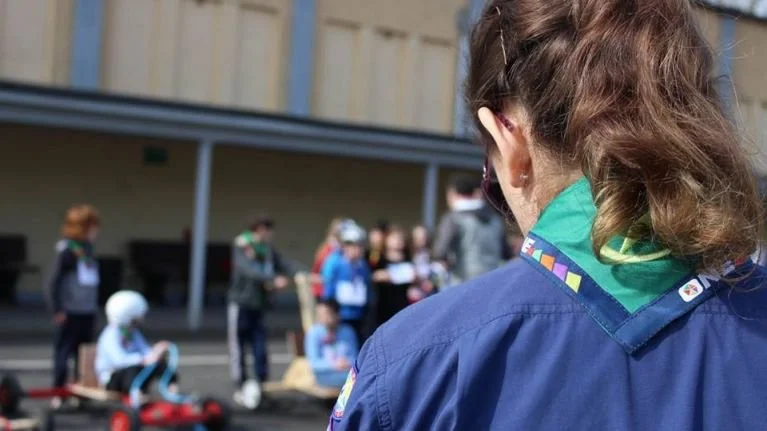 Girl in Girl Scout uniform observing children in a schoolyard