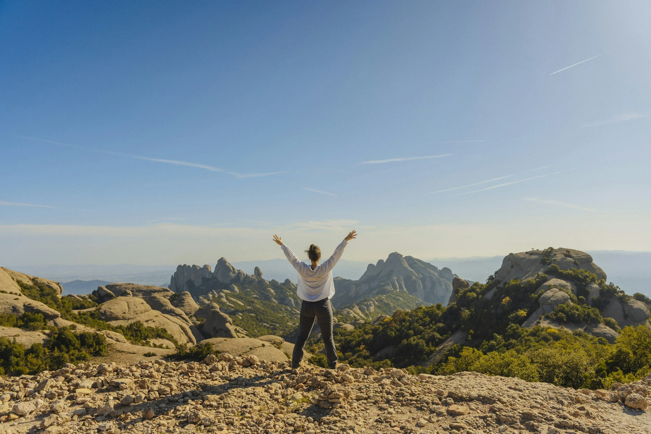 woman on walking trail on top of mountain with arms stretched out