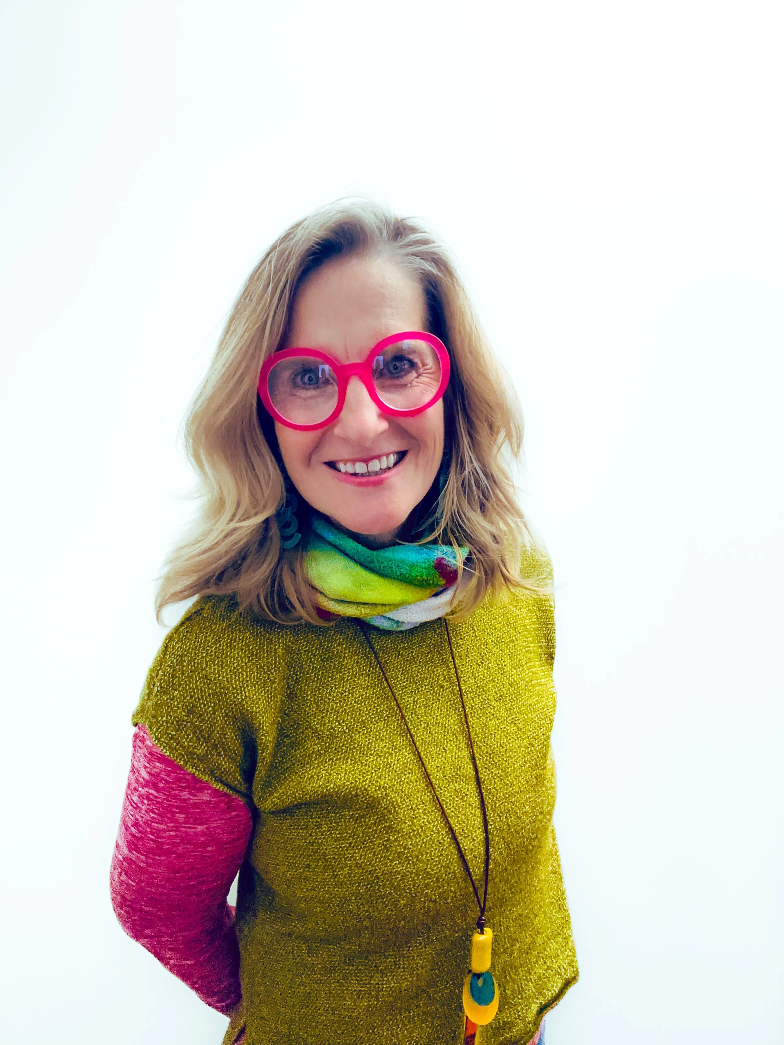 pamela in colorful clothes and pink glasses with hands behind her back