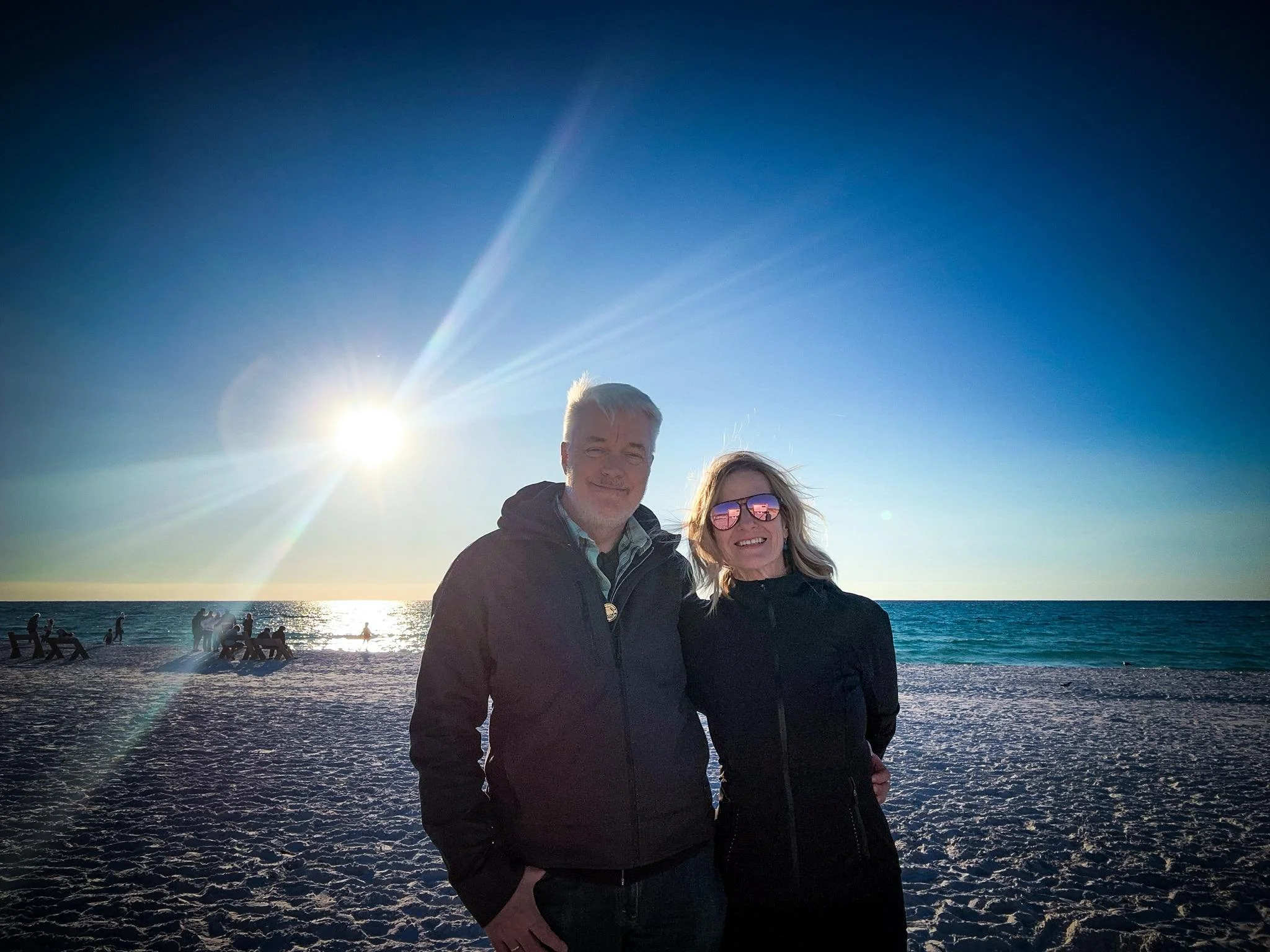 Pamela and her husband at Topsail Hill Preserve State Park posing on a beach in front of the Gulf of Mexico. Sunshine before sunset.
