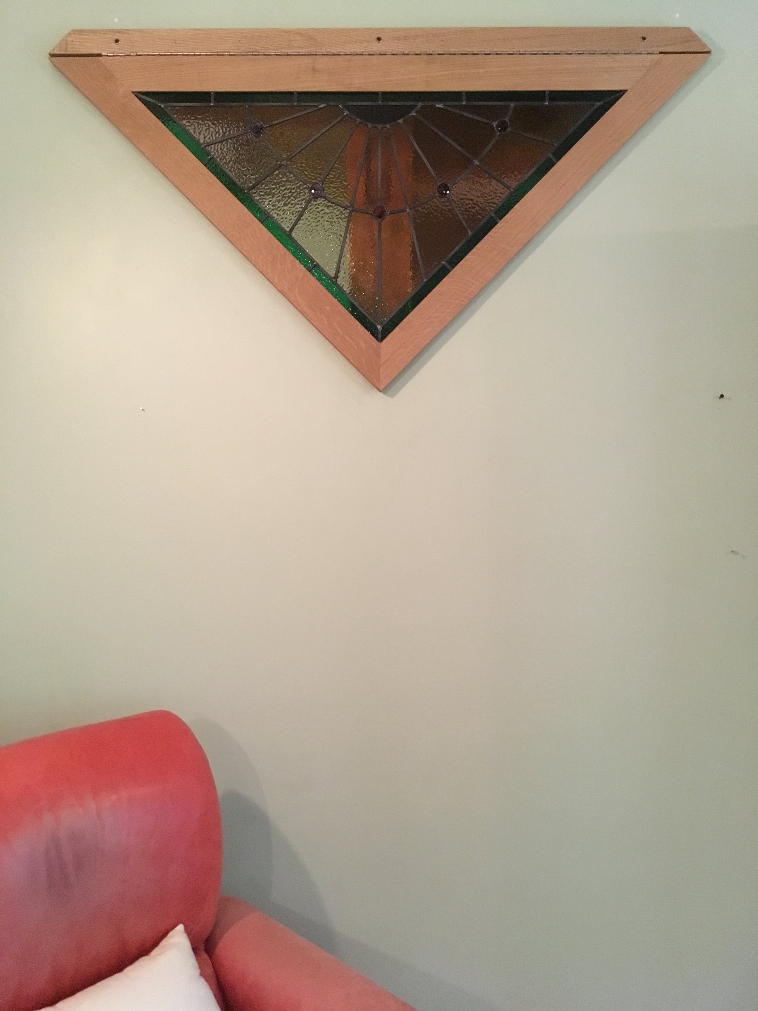 Decorative stained glass wall art with a wooden triangular frame.